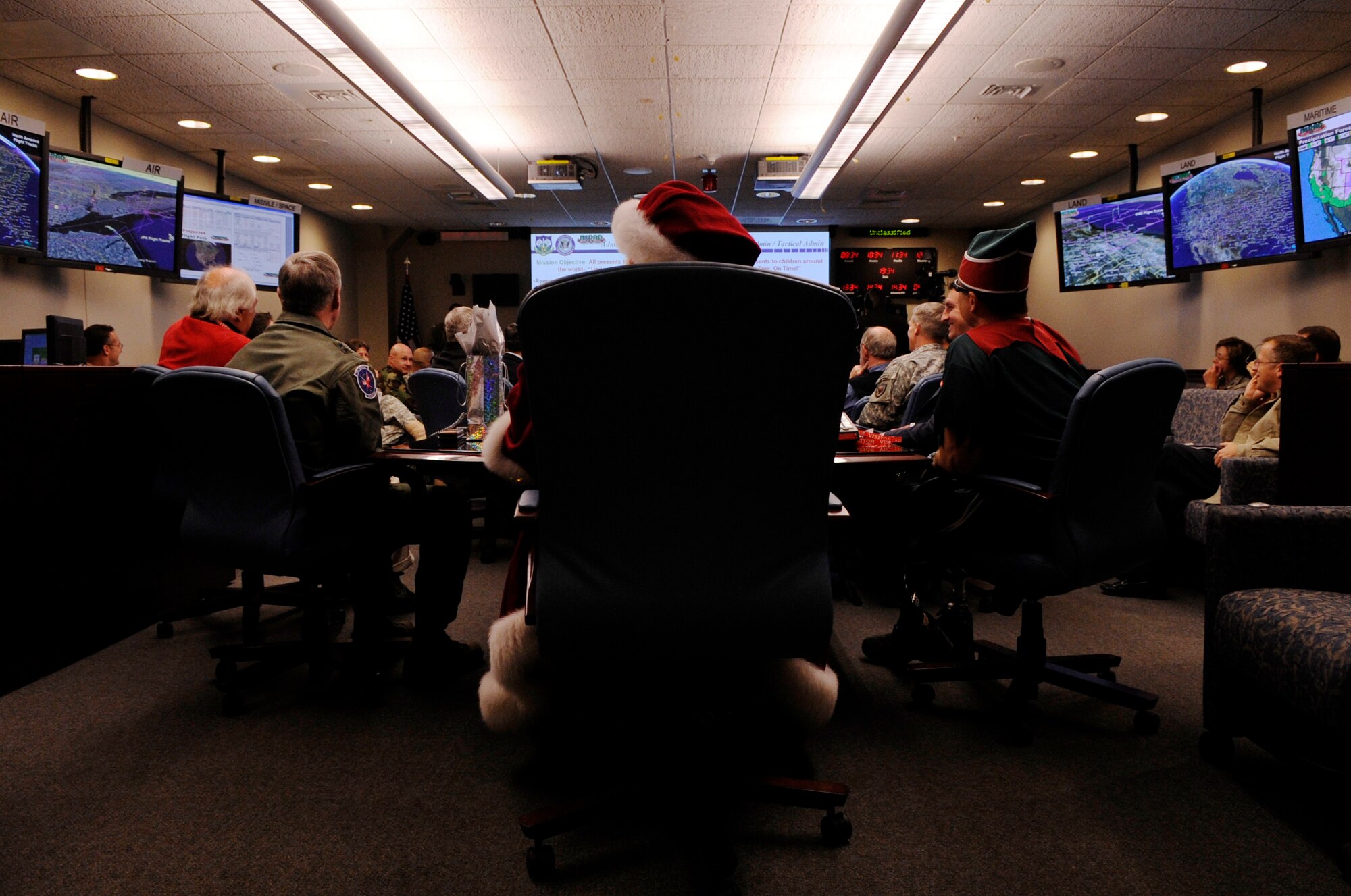 Santa Claus and Elf Dee make a surprise visit to the North American Aerospace Defense Command Tracks Santa Battle Cab Dec. 23 at Peterson Air Force Base, Colo. Santa received Federal Aviation Administration, weather and air mission briefs. (U.S. Air Force photo/Staff Sgt. Desiree N. Palacios) 