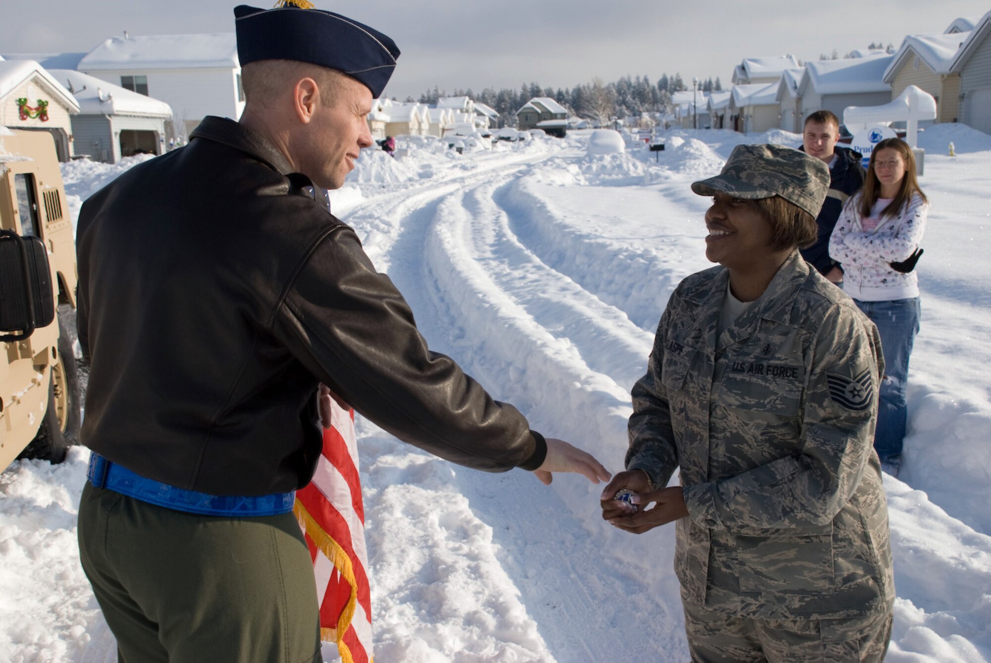 AIRWAY HEIGHTS, Wash. – Tech. Sgt. Michele Glaspie, from the 92nd Aeromedical Dental Squadron, receives a coin from the 92nd Air Refueling Wing vice commander, Col. Blaine Holt,  after a reenlistment ceremony in front of the Sergeant’s home Dec. 19. Colonel Holt, Chief Master Sgt. David Nordel, the 92nd ARW command chief, and Lt. Col. Paul Nelson, the 92nd AMDS commander, journeyed to the sergeant’s home to carry out the reenlistment ceremony when she was unable to make it to base due to severe weather conditions. The entourage arrived in a Humvee to navigate through the snow. (U.S. Air Force photo / Staff Sgt. Mikel Daniel)