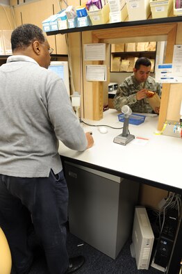 WHITEMAN AIR FORCE BASE, Mo. - Retiree Ernest Carpenter, 509th Medical Group pharmacy technician, hands off a prescription Dec. 16 after an inspecting the prescription content. Mr. Carpenter inspects every prescription before it is sent out to the customer to ensure that the correct medication was provided and the correct dosage has been labeled on the pill bottle. (U.S.  Air Force photo/Airman 1st Class Carlin Leslie)