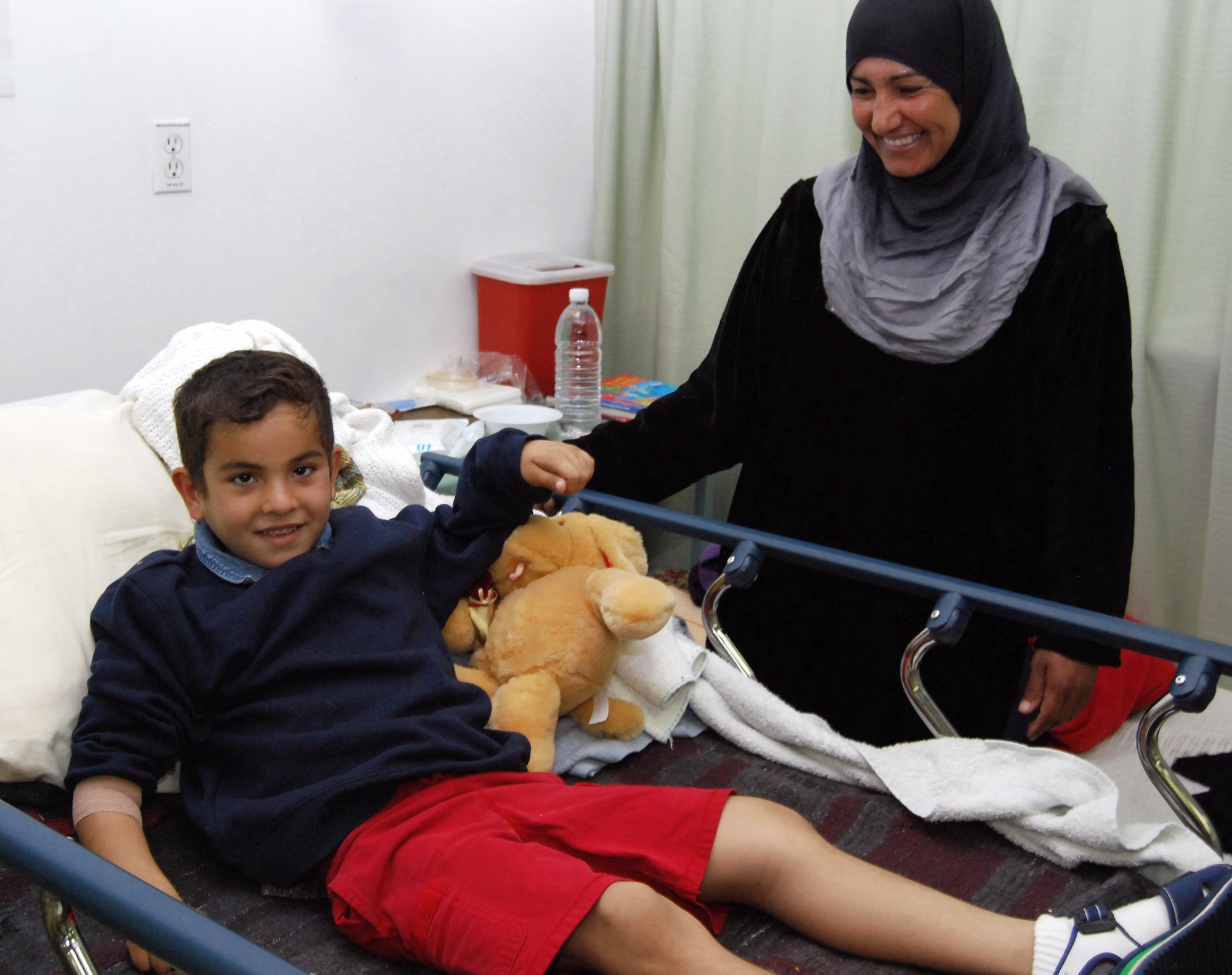 Mustafa Jasim smiles for a photograph in the Air Force Theater Hospital's intermediate care ward at Joint Base Balad, Iraq, Dec. 20. Mustafa, his brother Ali, and a third patient, Dhafir Kurdi Hilal, were aeromedically transported from Balad to the 86th Combat Support Hospital in Baghdad via Iraqi air force Mi-17 Hip helicopters. Also pictured here is Mustafa's mother, Saadia Ibaid Jasim. (U.S. Air Force photo/Staff Sgt. Don Branum)