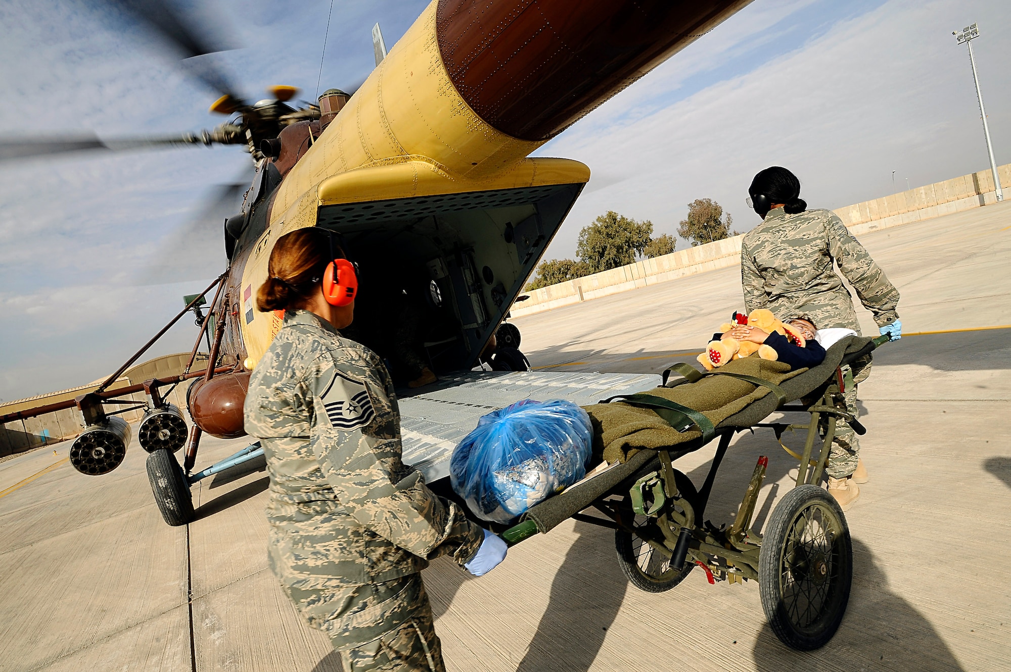 Master Sgt. Ana Ortiz (left) and Master Sgt. Diana Nelson transport Mustafa Jasim to an Iraqi air force Mi-17 Hip helicopter at Joint Base Balad, Iraq, Dec. 20. Mustafa, his brother Ali and an Iraqi police officer were transported from Balad to the 86th Combat Support Hospital in Baghdad. Sergeant Ortiz, the 332nd Expeditionary Logistics Readiness Squadron Personnel Support for Contingency Operations superintendent, and Sergeant Nelson, the PERSCO NCO in charge, are deployed from the Connecticut Air National Guard's 103rd Airlift Wing. (U.S. Air Force photo/Airman 1st Class Jason Epley) 