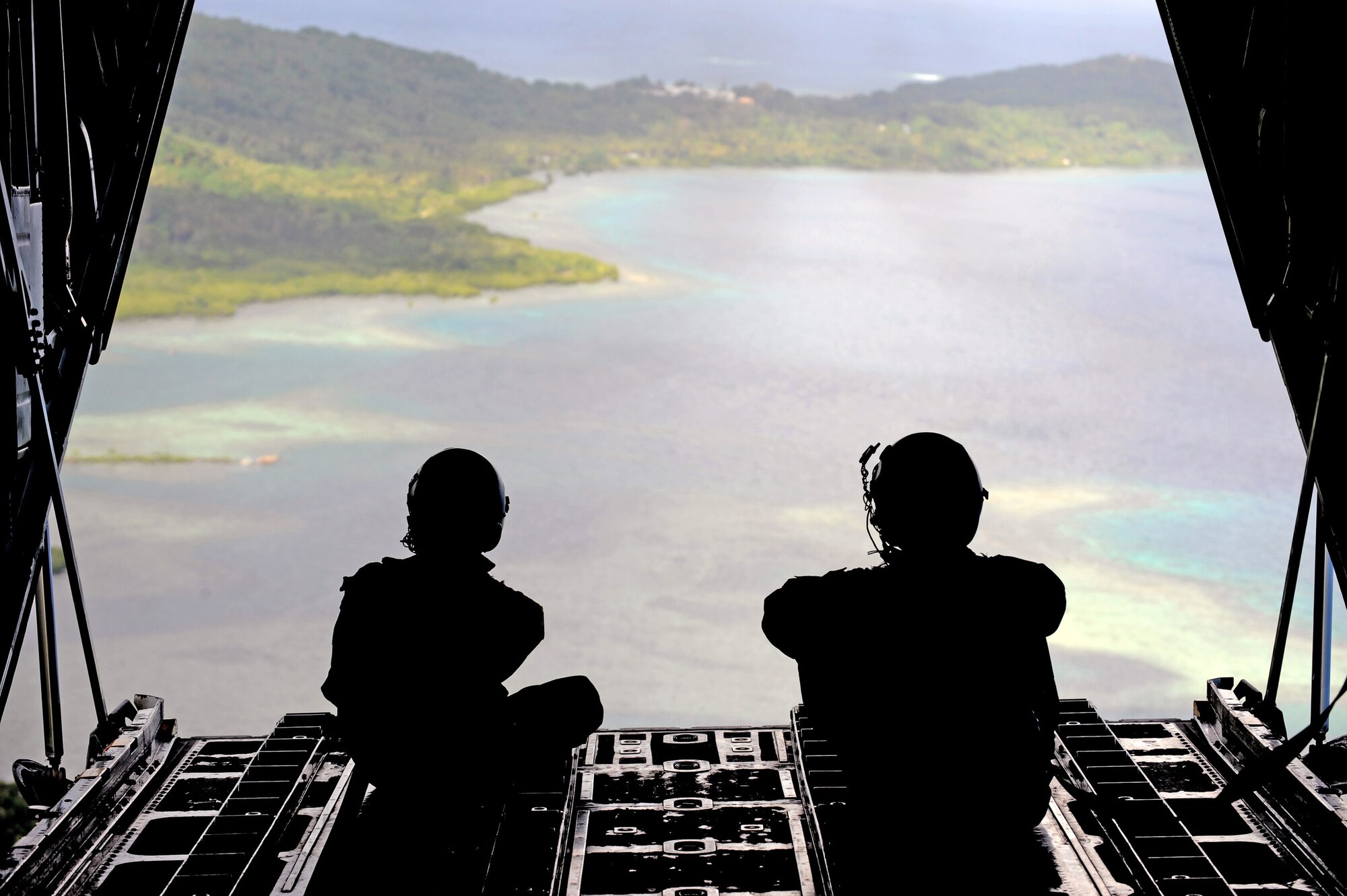 Senior Airman Robert Gore and Airman 1st Class Dustin Deveaux observe the drop zone from a C-130 Hercules during Operation Christmas Drop Dec. 19 over the remote Island of Yap. In all, more than 180 boxes were built for the humanitarian mission, making 2008 one of the largest drops in Operation Christmas Drop's 57-year history. Airmen today continue the tradition of delivering supplies to remote islands of the Commonwealth of the Northern Marianas Islands, Yap, Palau, Chuuk and Pohnpei. Airmen Gore and Deveaux are crewmembers are from the 36th Airlift Squadron from Yokota Air Base, Japan.  (U.S. Air Force photo/Master Sgt. Kevin J. Gruenwald)
