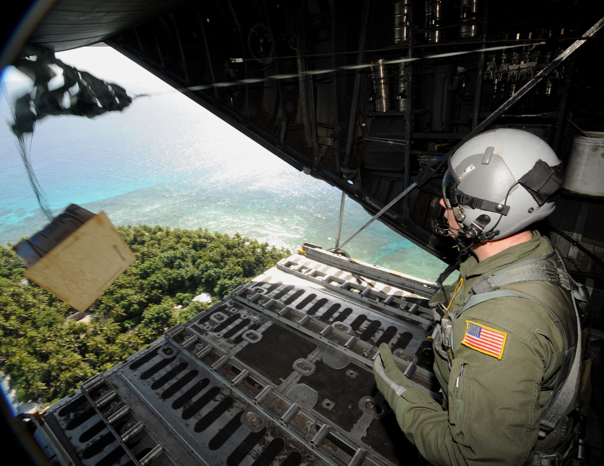 Tech. Sgt. Heath Bahyi observes boxed cargo being airdropped from a C-130 Hercules during Operation Christmas Drop Dec. 19 over the remote Island of Yap. Airmen today continue the tradition of delivering supplies to remote islands of the Commonwealth of the Northern Marianas Islands, Yap, Palau, Chuuk and Pohnpei. In all, more than 180 boxes were built for the humanitarian mission, making 2008 one of the largest drops in Operation Christmas Drop's 57-year history. Sergeant Bahyi is a loadmaster from the 36th Airlift Squadron from Yokota Air Base, Japan. (U.S. Air Force photo/Master Sgt. Kevin J. Gruenwald) 