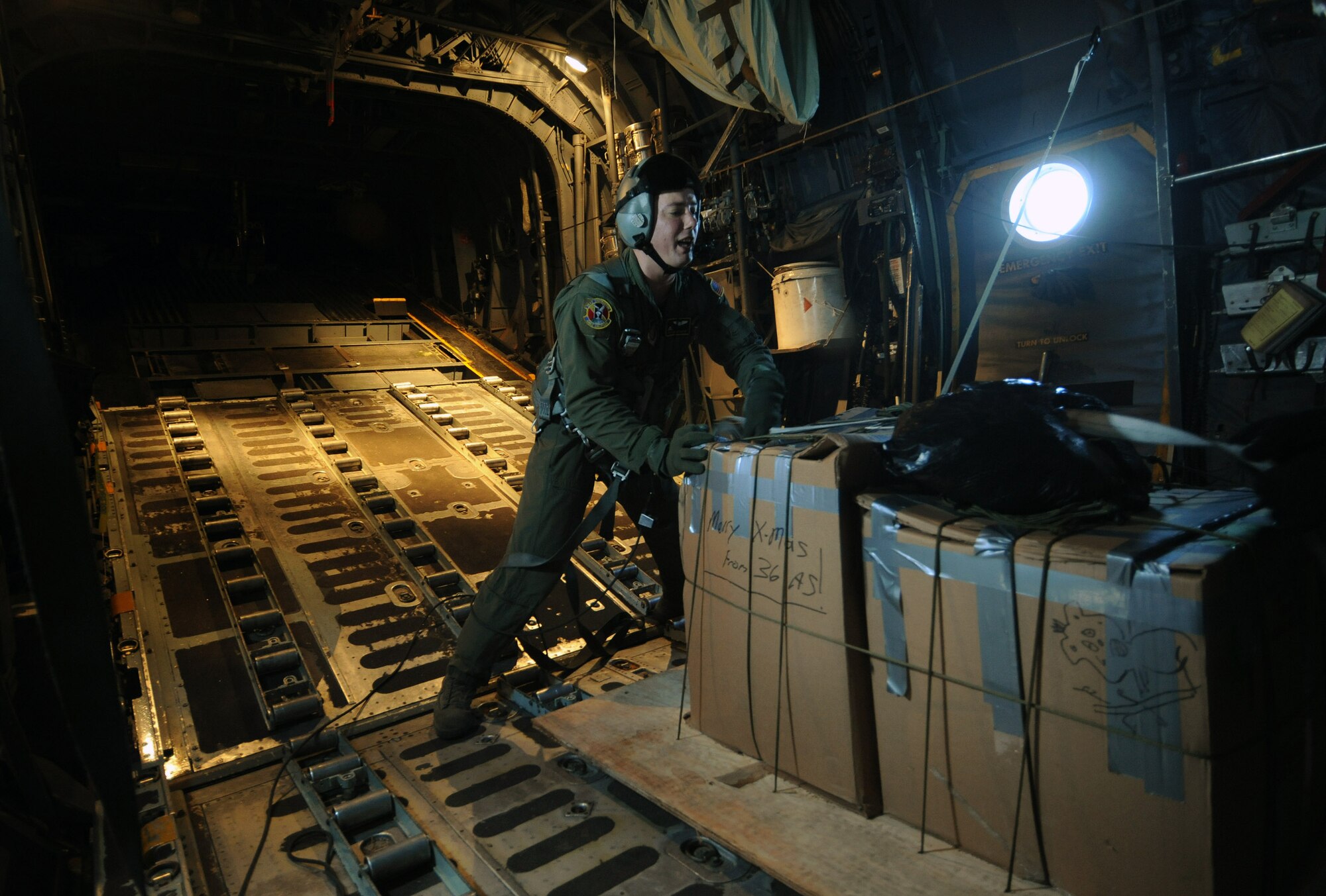 Tech. Sgt. Heath Bahyi pushes boxes of donated goods in place on a C-130 Hercules during Operation Christmas Drop Dec. 19 over the Pacific Ocean. Airmen today continue the tradition of delivering supplies to remote islands of the Commonwealth of the Northern Marianas Islands, Yap, Palau, Chuuk and Pohnpei. In all, more than 180 boxes were built for the humanitarian mission, making 2008 one of the largest drops in Operation Christmas Drop's 57-year history. Sergeant Bahyi is a loadmaster from the 36th Airlift Squadron from Yokota Air Base, Japan. (U.S. Air Force photo/Master Sgt. Kevin J. Gruenwald)