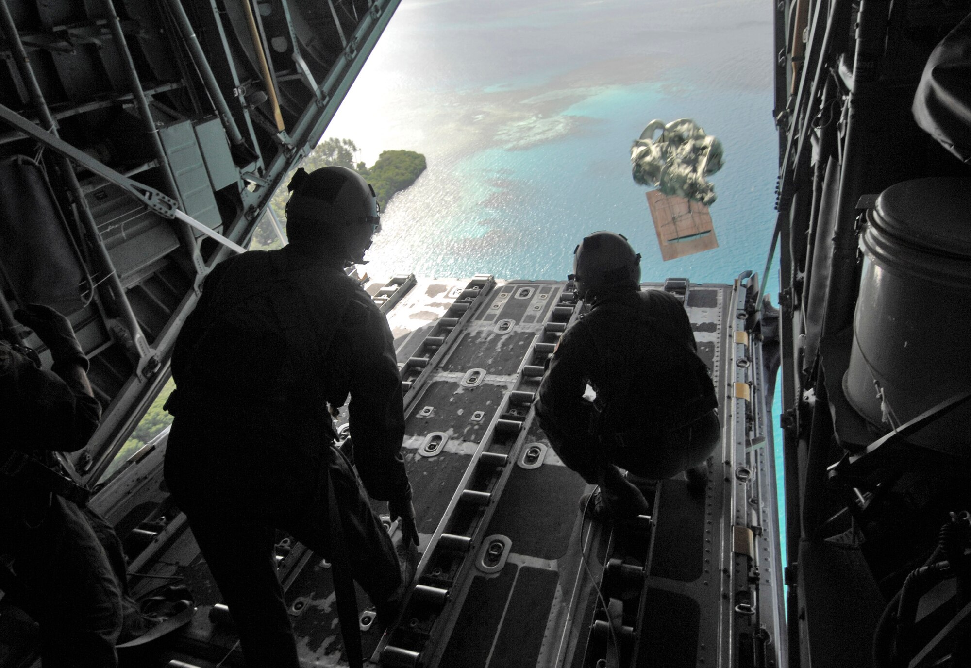 Senior Airman Robert Gore and Airman 1st Class Dustin Deveaux push out a pallet of donated goods from a C-130 Hercules during Operation Christmas Drop Dec. 19 over the Pacific islands of Chuuk. In all, more than 180 boxes were built for the humanitarian mission, making 2008 one of the largest drops in Operation Christmas Drop's 57-year history. Airmen today continue the tradition delivering supplies to remote islands of the Commonwealth of the Northern Marianas Islands, Yap, Palau, Chuuk and Pohnpei. Airmen Gore and Deveaux are loadmasters from the 36th Airlift Squadron from Yokota Air Base, Japan. (U.S. Air Force photo/Master Sgt. Kevin J. Gruenwald)