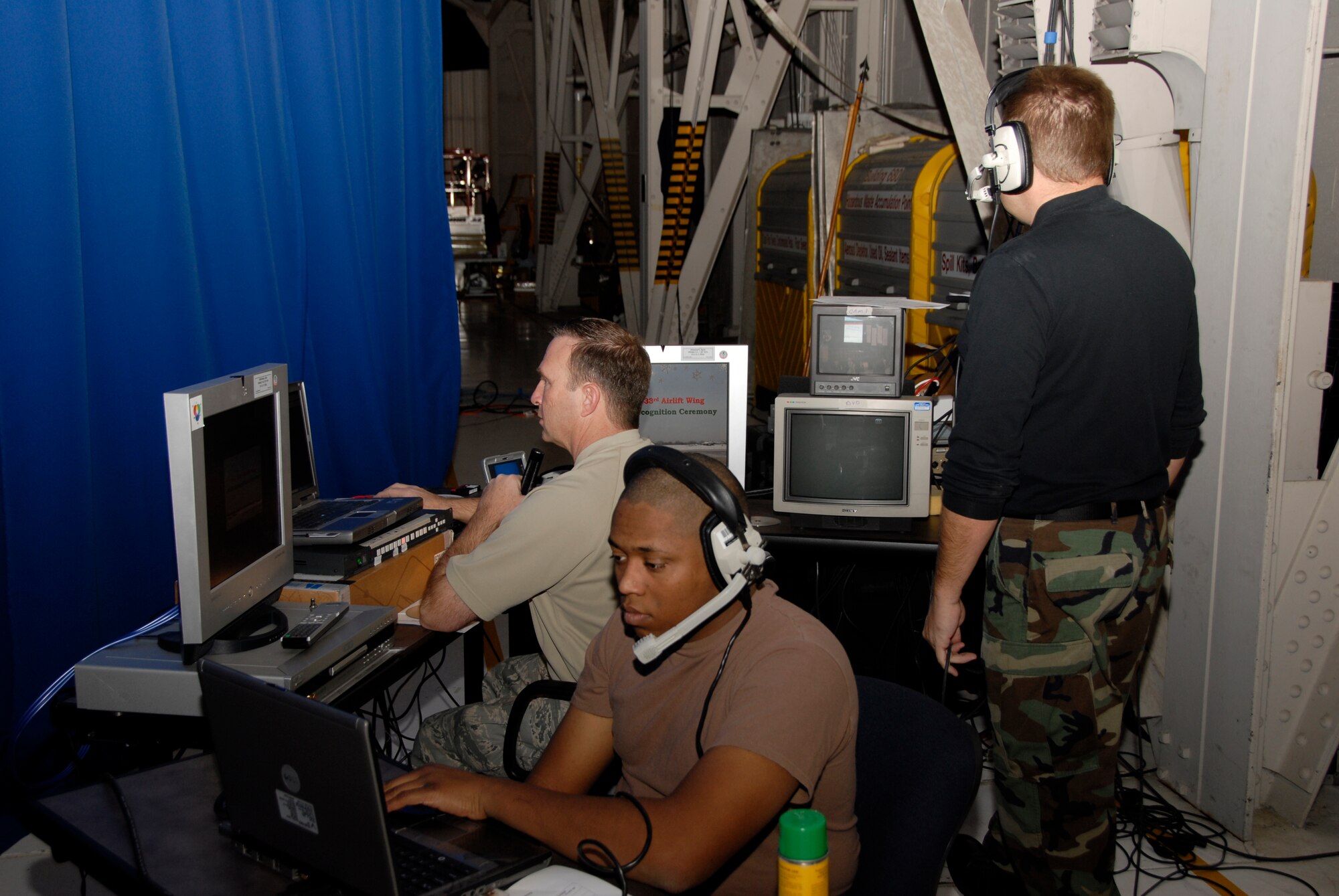 Members of the 133rd AW Public Affairs staff enhance the messages by putting images of speakers and videos on big screens during the 133rd Airlift Wing Recognition Ceremony on Dec. 13, 2008. Master Sgt. Dave Fenner, right, directs Airmen from the 133rd Communications Flight, 133rd Civil Engineering Squadron and 133rd Airlift Wing Headquarters on cameras, audio and lighting positions on the audience side of the curtain. Behind the stage Senior Airman K.C. Veillon, center, brings up the slides and Senior Master Sgt. Mark Moss sends the sources to the screens. The Minnesota Air National Guard unit in St. Paul holds a ceremony every year recognizing the accomplishments of the Airmen, their families, and others in the community who make the 133rd AW very successful. (USAF photo by Tech. Sgt. Tyrell Heaton)