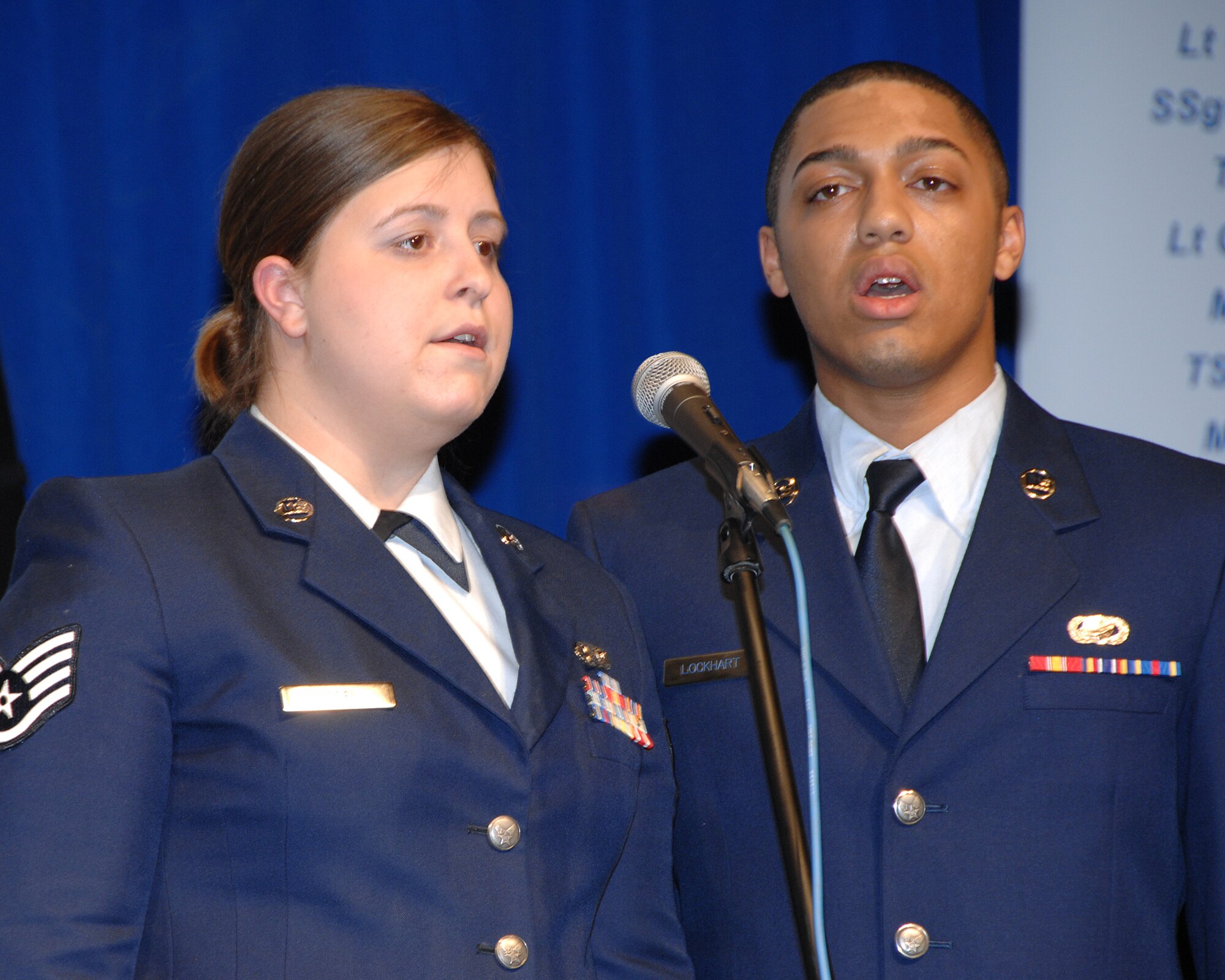 Staff Sgt. Karly Vogel, 133rd Airlfit Wing Headquarters, and Airman First Class David Lockhart, 133rd Mission Support Squadron, sing the National Anthem during the 2008 Wing Recognition Ceremony in a hangar on the St. Paul Air National Guard Base on Dec. 13, 2008. (USAF photo by Tech. Sgt. John Wiggins)