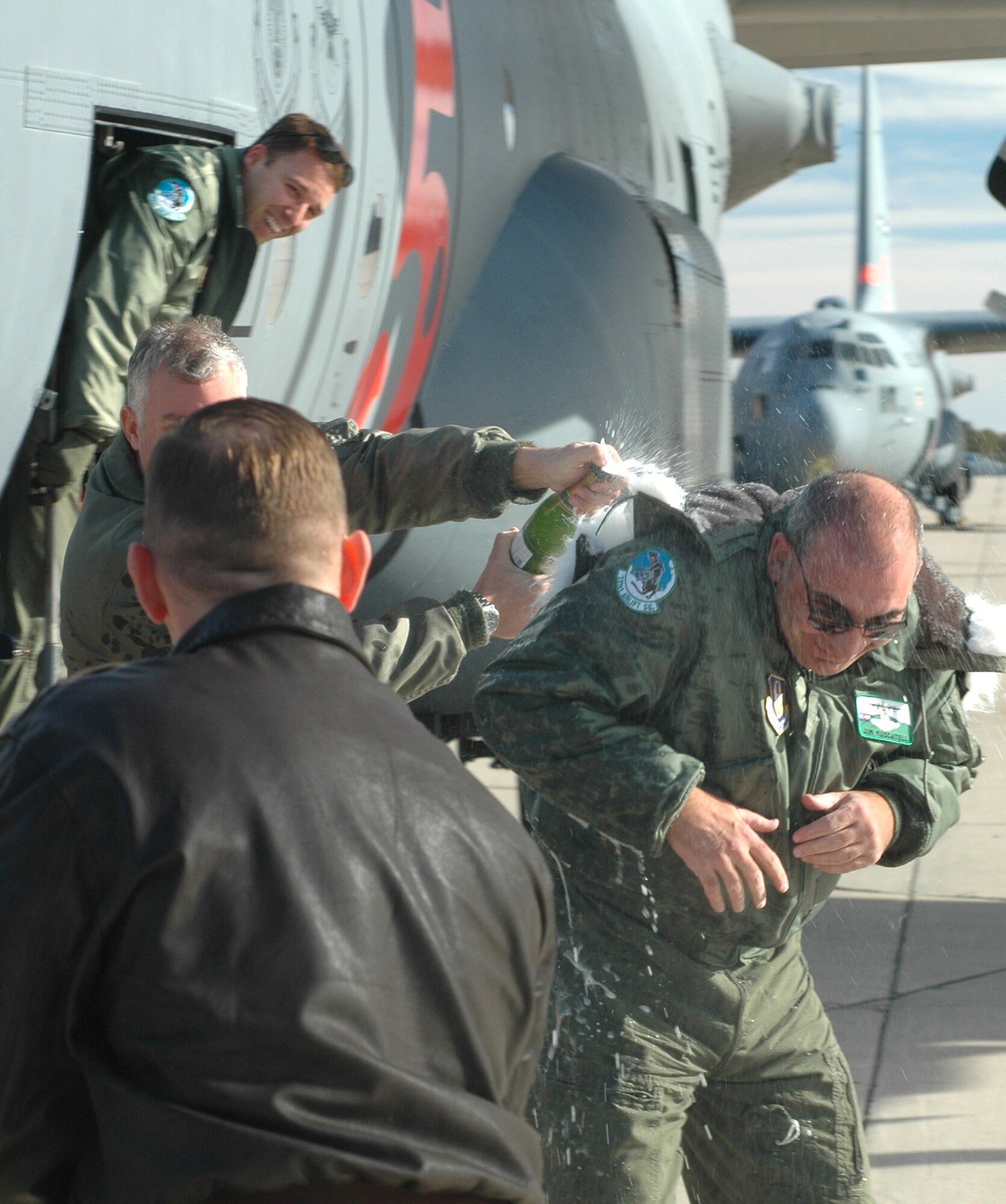 Maj. Richard Pantusa (foreground) and Lt. Col. Dan Mullins (background, left) shower down Col. James J. Muscatell, Jr., 302nd Airlift Wing commander with ceremonial champagne Dec. 22, 2008, at Peterson Air Force Base, Colo. Colonel Muscatell, commander of the airlift wing, performed his final flight before taking command of the 403rd AW at Keesler AFB, Miss., slated for mid-January 2009. Known as a "fine flight," a pilot is congratulated and recognized for their service to their squadron with a ceremonial gathering directly after the flight. Colonel Mullins is a chief pilot and Major Pantusa is a pilot scheduler. Both are assigned to the 731st Airlift Squadron. (U.S. Air Force photo/Stephen J. Collier)