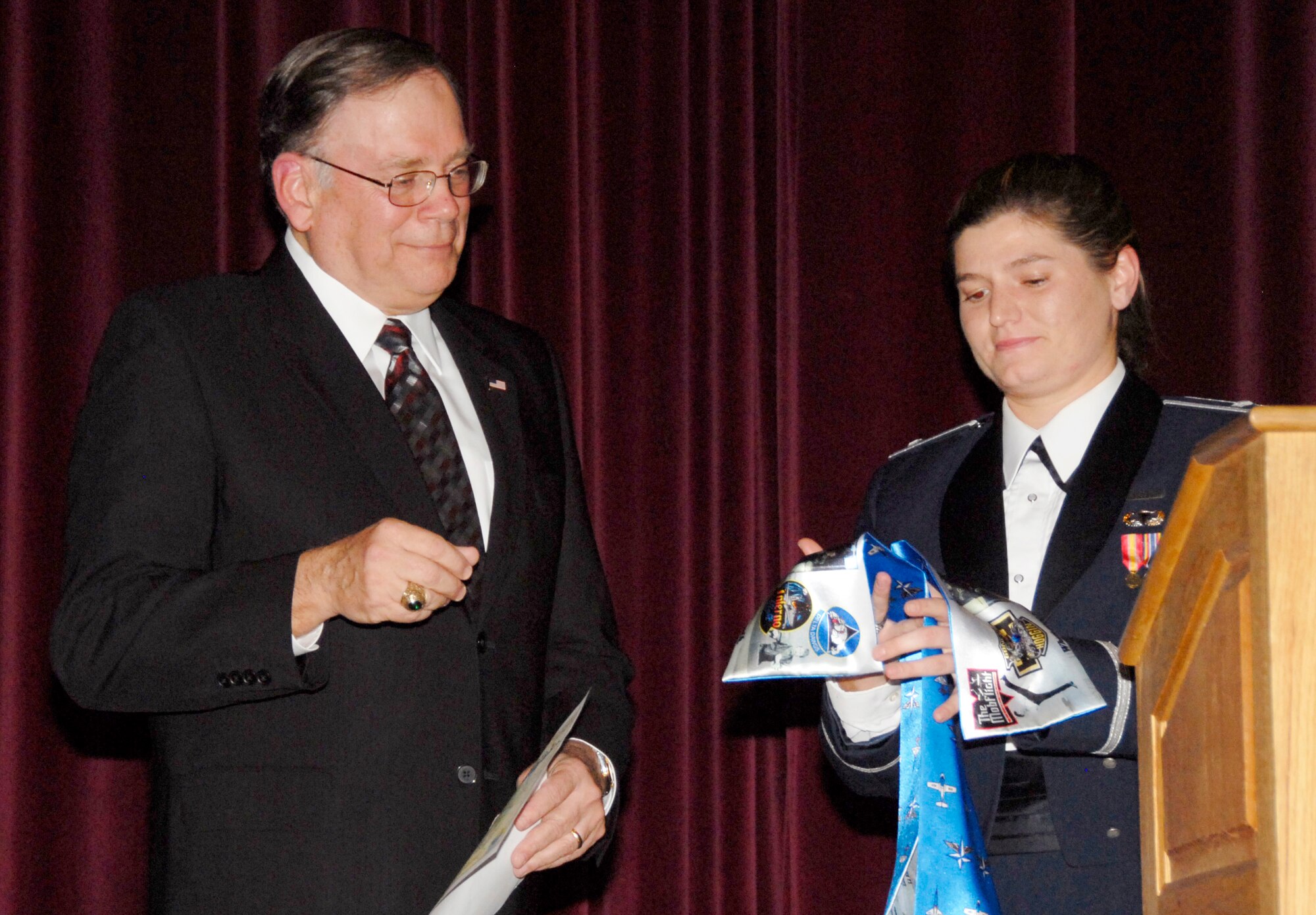 First Lt. Bridgett Whiting, leader of Euro-NATO Joint Jet Pilot Training Program Class 09-01, presents Gen. (ret.) John Jumper, former Air Force Chief of Staff, with a class scarf and present during the class's graduation Dec. 19 at the base theater. General Jumper told the graduating class that the keys to success are focusing on the job right now, be an officer first and remember family. (U.S. Air Force photo/Harry Tonemah)