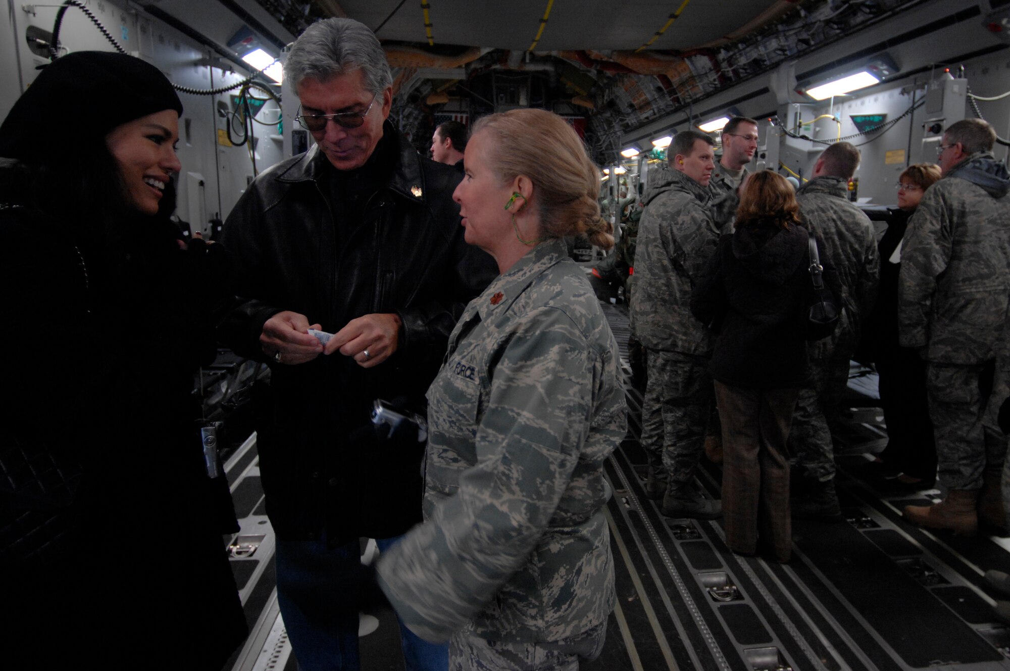 Michael Buffer (middle), professional ring announcer for boxing and wrestling matches, his wife Christine, and Maj. Laurie Turner (right), Contingency Aeromedical Staging Facility deployed troop commander, visit with wounded warriors on a C-17 Globemaster aircraft before they leave, Dec. 16, 2008, Ramstein Air Base, Germany. (U.S. Air Force photo by Senior Airman Amber Bressler)