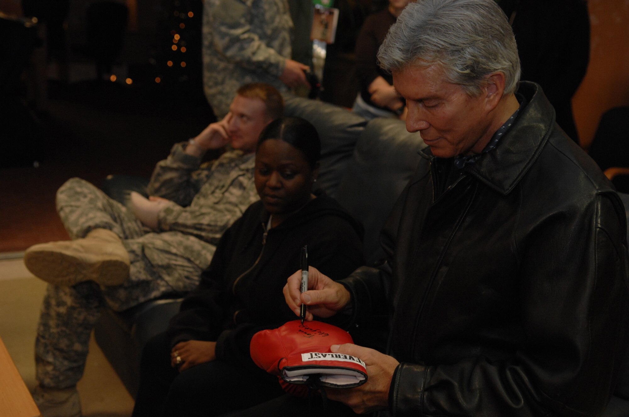 Michael Buffer, professional ring announcer for boxing and wrestling matches, signs a glove for a patient in the United Service Organization located in the Contingency Aeromedical Staging Facility, Dec. 15, 2008, Ramstein Air Base, Germany.  The CASF operates all hours of the day and has performed 85,000 patient movements in support of Operations Enduring Freedom and Iraqi Freedom. (U.S. Air Force photo by Senior Airman Amber Bressler)