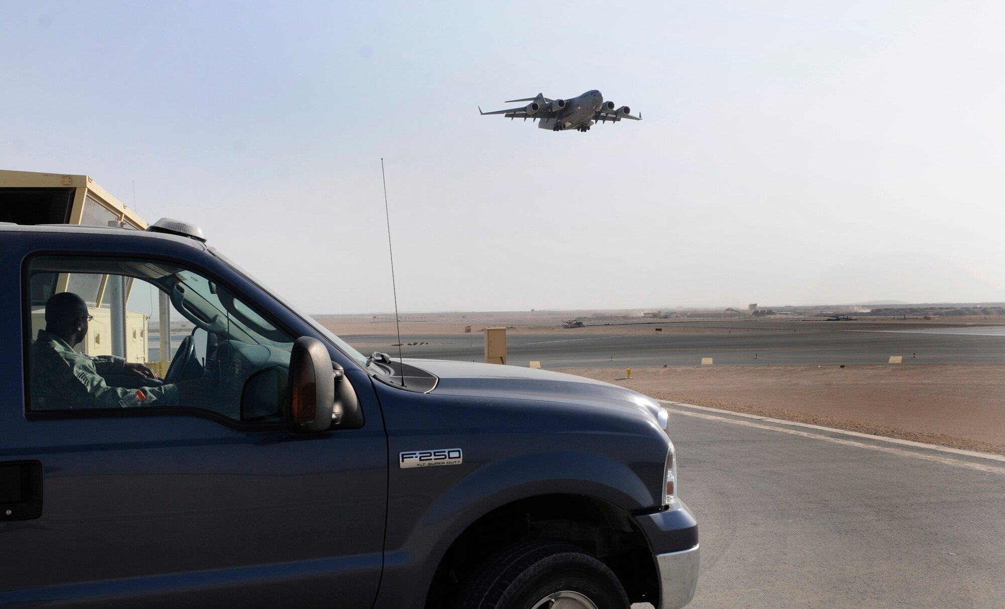 Tech. Sgt. Antonio Cooper, deputy airfield manager assigned to the 379th Expeditionary Operations Support Squadron, observes a C-17 Globemaster III coming in for a landing, Dec. 15, 2008, at an undisclosed air base in Southwest Asia. After the aircraft has landed, Sergeant Cooper inspects the runway for debris. The runway is checked at least once every two hours and more often when needed. Sergeant Cooper is a native of Stapleton, Ga., and  is deployed from Patrick Air Force Base, Fla. (U.S. Air Force photo by Tech. Sgt. Michael Boquette)