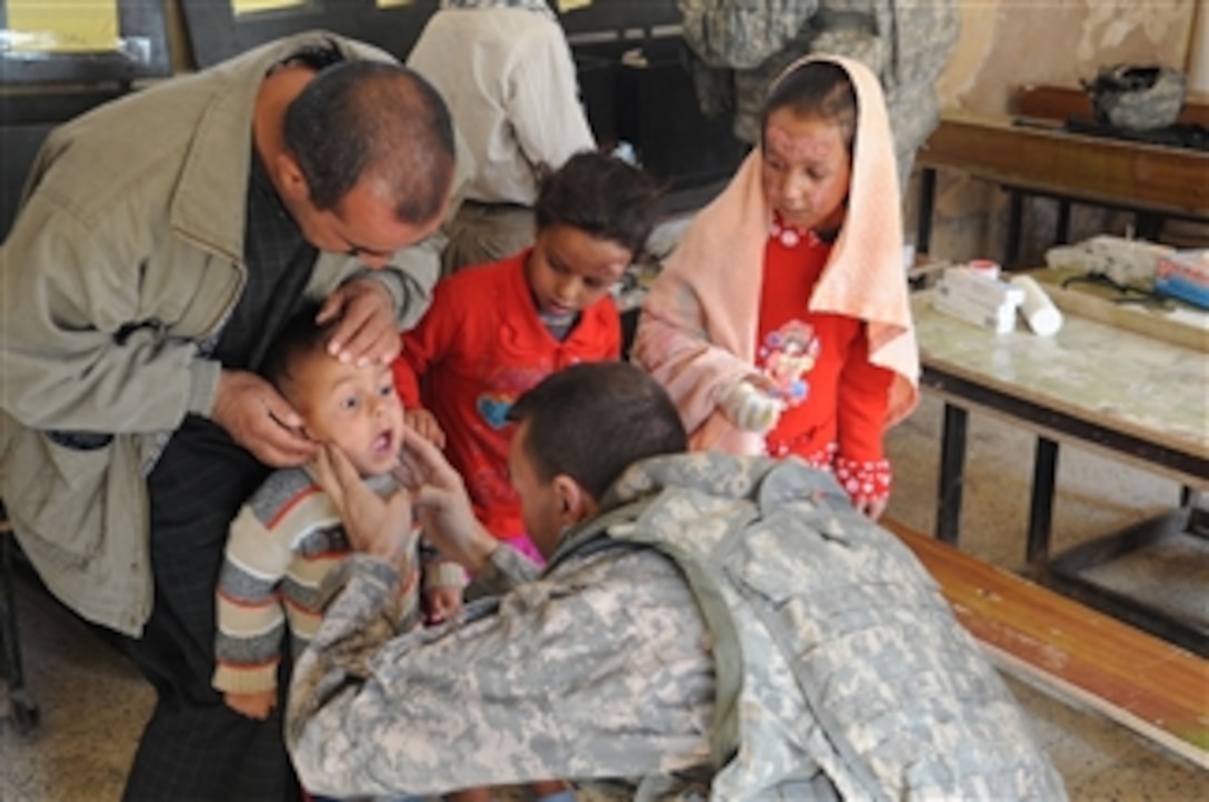 A U.S. Army doctor attached to the 2nd Brigade Combat Team, 25th Infantry Division examines a young boy at the Fira Shia Tabuq Primary School in Samalaat, Iraq, during a combined medical engagement on Dec. 15, 2008.  