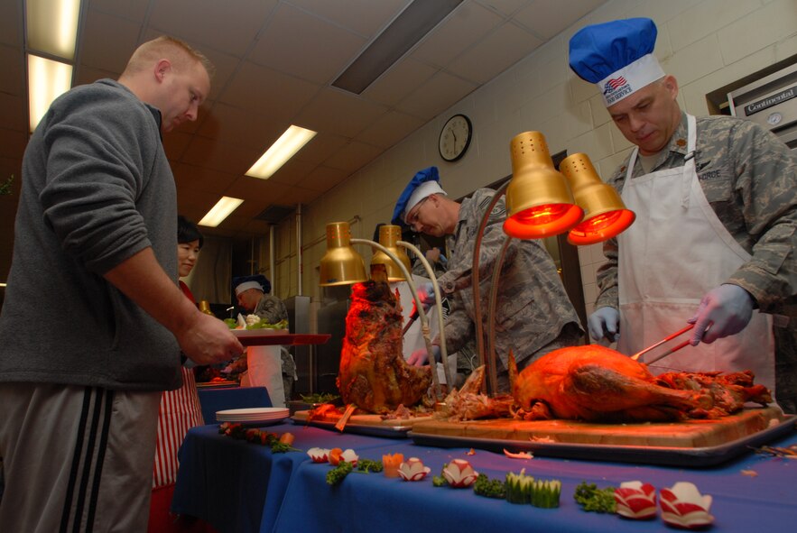 KUNSAN AIR BASE, Republic of Korea -- Chief Master Sgt. Michael Mezick, 8th Communications Squadron, and Chap. (Maj.) John Kenyon, 8th Fighter Wing chaplain, serve Christmas Lunch to Kunsan Airmen and Soldiers, Dec. 25, 2008. A holiday tradition around the Air Force, wing leadership switched places with dining facility staff and served lunch to Wolf Pack members. (Photo by Senior Airman Angela Ruiz)