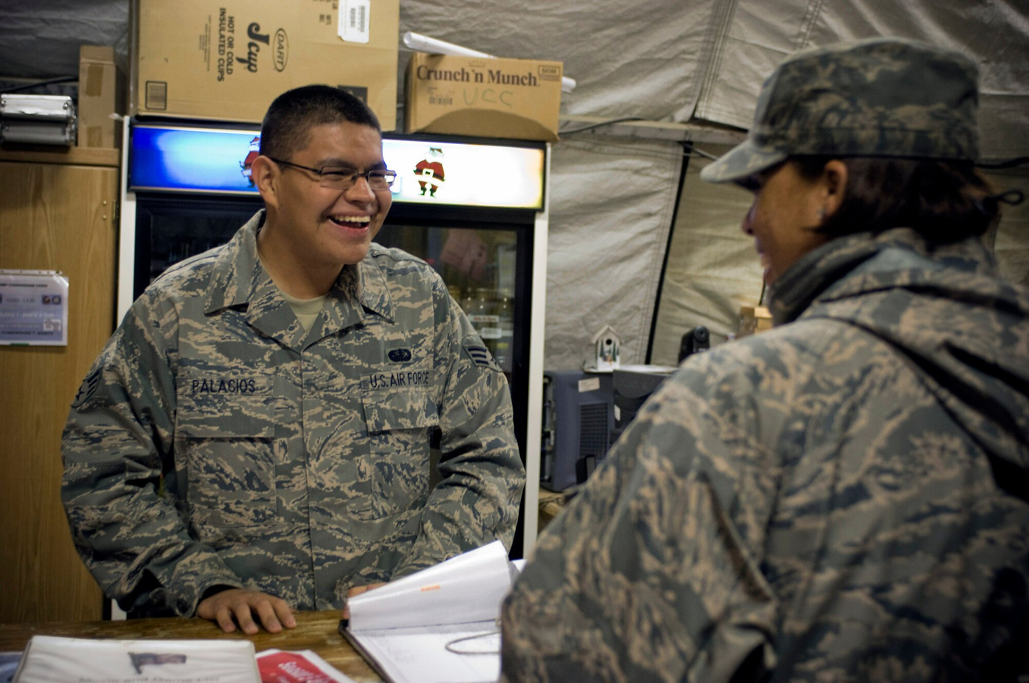 Senior Airman Marco Palacios helps a customer in the services tent Dec. 17 at Bagram Airfield, Afghanistan. Airman Palacios, deployed from Beale Air Force Base, Calif., made an effort to improve morale for deployed Airmen over the holidays by taping readings of "A Night Before Christmas," and creating e-cards of Airmen's picture with Santa. Airman Palacios is a services technician with the 455th Expeditionary Force Support Squadron. (U.S. Air Force photo/Staff Sgt. Rachel Martinez) 
