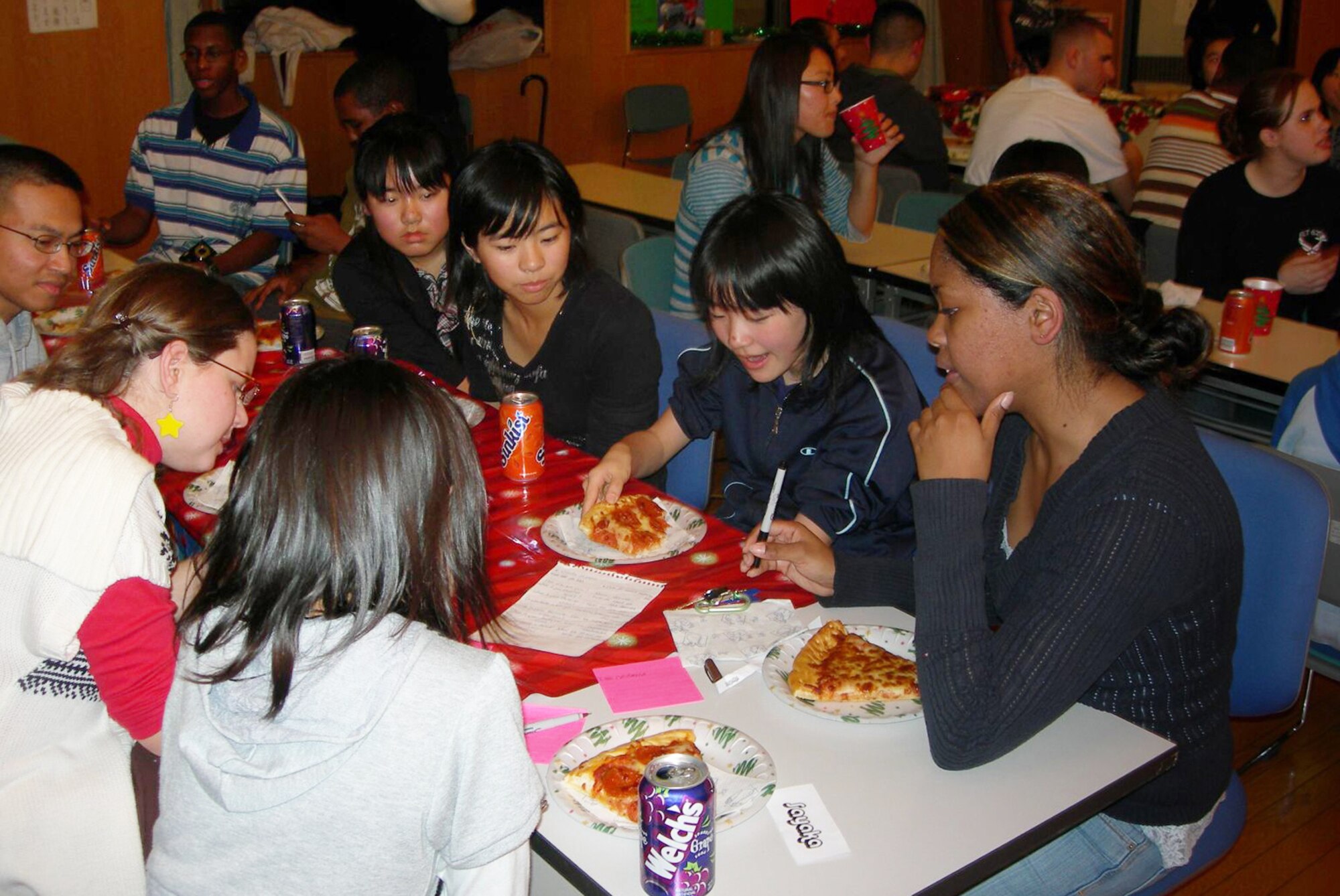MISAWA AIR BASE, Japan -- Risako Hoshi, Momoishi Elementary School fifth-grader, and Airman 1st Class Victoria Hobbs, 35th Logistics Readiness Squadron, munch on pizza while sharing English and Japanese phrases with each other during the "I want to get to know you better" questions and answer time during the 16th Annual Oirase Town and Misawa Air Base sixth-grade Children's Cultural Exchange Christmas party Dec. 6, 2008. Airman Hobbs is the president of the Misawa First Four. (Courtesy photo by Simon Bernard) 
