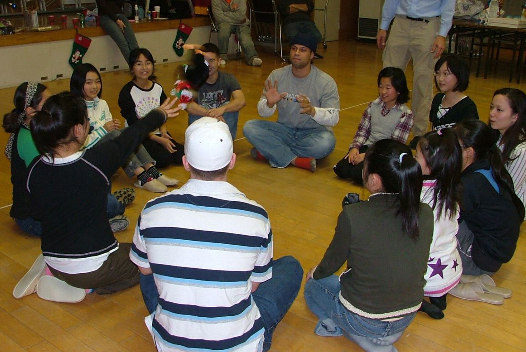 MISAWA AIR BASE, Japan -- Senior Airman Felix Colon, 35th Civil Engineer Squadron firefighter, prepares to catch the "hot penguin" from Mina Tanikawa, Shimoda Elementary School fifth-grader, at the Oirase North Community Center Dec. 1, 2008. Hot penguin is a Christmas version of the hot potato game put on by the Airmen Leadership School. (Courtesy photo by Simon Bernard)