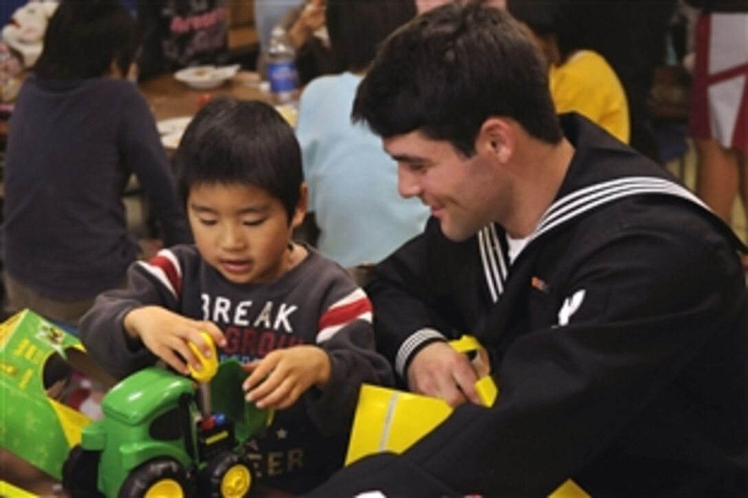 U.S. Navy Petty Officer 3rd Class James R. Wilkerson, assigned to the amphibious command ship USS Blue Ridge watches as a child from the Children's Home Shunko Gakusen tests out his new toy, Yokosuka, Japan, Dec. 20, 2008. The USS Blue Ridge serves under Commander, Expeditionary Strike Group 7, Task Force 76, the Navy's only forward deployed amphibious force.