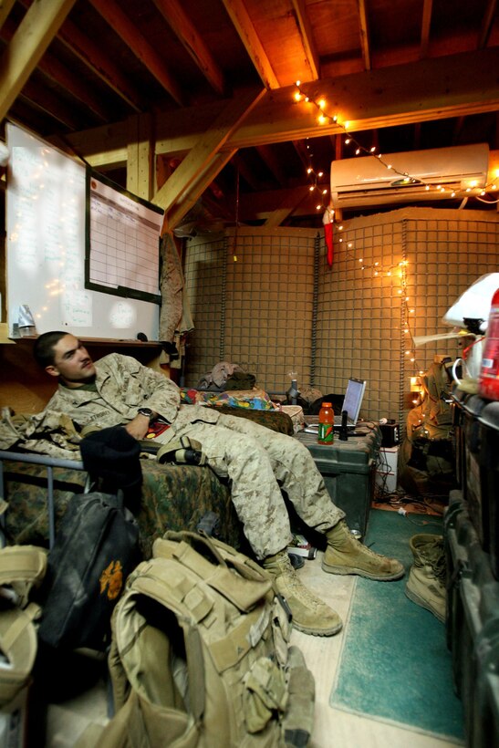 Lance Cpl. Tyler Strobel, 21, a driver with Mobile Section Jump Bravo, Headquarters and Service Company, Task Force 3rd Batalion, 7th Marine Regiment, Regimental Combat Team 5, spends Christmas Eve reading at his festively decorated "home" at Combat Outpost Ubaydi, Iraq.  Many Marines dressed their living areas and offices with stockings, ornaments and lights to get into the holiday spirit.::r::::n::