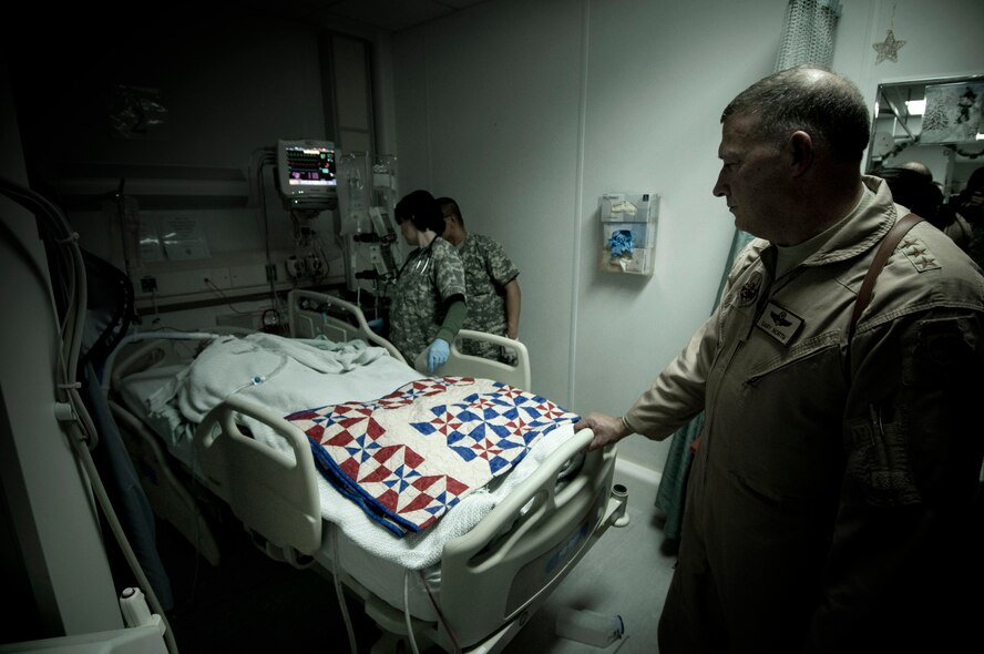 Lt. Gen. Gary North, U.S. Air Forces Central commander, watches over a wounded Airman at Bagram Air Field, Afghanistan, Christmas Eve, Dec. 24. General North personally presented the Airman with his Purple Heart medal, as well a special quilt made with love by "little old ladies" in South Carolina. The eager staff at the military hospital can treat his wounds, but the quilt serves to heal his mind and spirit -- a constant reminder that there are people who care, even if they have never met. (U.S. Air Force photo by Staff Sgt. Samuel Morse)(Released)