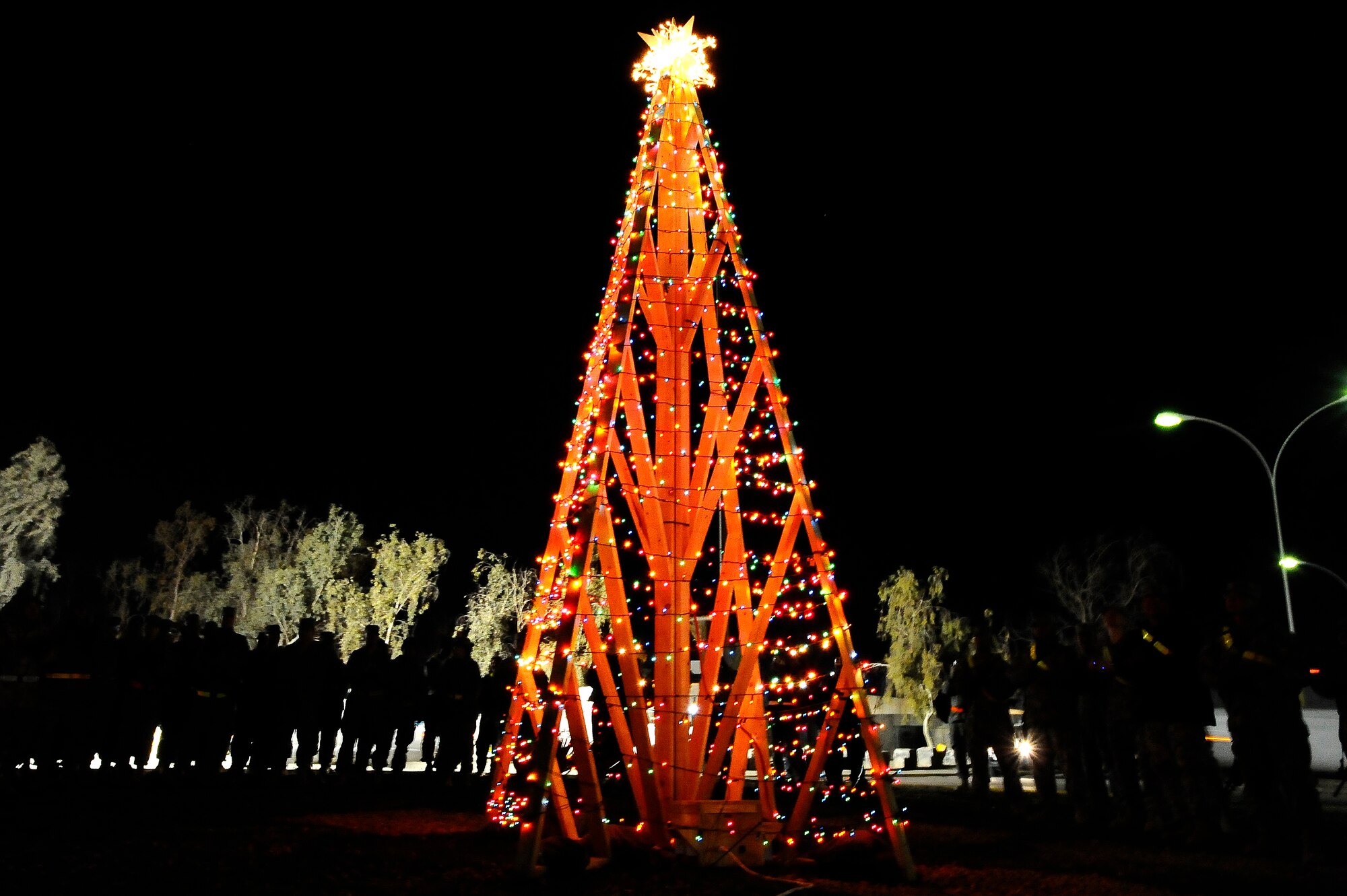 Airmen and Soldiers stand around the Joint Base Balad, Iraq, holiday tree during a tree-lighting ceremony inside Sapper Circle here Dec. 16. During the ceremony, commanders from the Air Force and Army judged large plywood holiday greeting cards, with the theme "Sounds of the Season," that various units across Balad had built. The winner of the competition will be announced on Christmas Day. (U.S. Air Force photo/Airman 1st Class Jason Epley)

