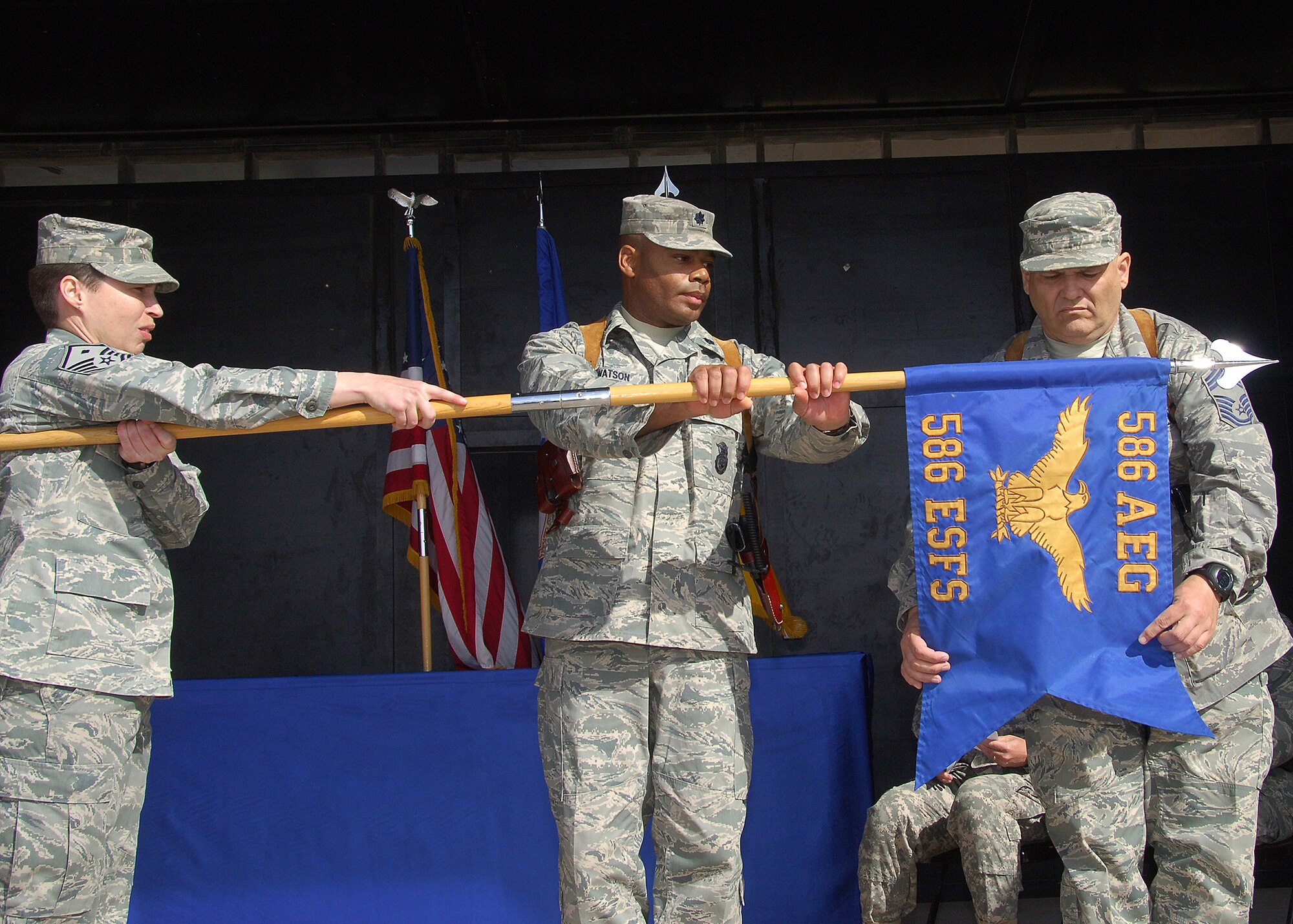 CAMP BUCCA, IRAQ -- Chief Master Sgt. Joseph Arico, right, Lt. Col. Bruce Watson, and Master Sgt. Joanne Reed, 586th Expeditionary Security Forces Squadron senior leaders, furl the flag of the squadron for the last time at the inactivation ceremony on Dec. 22. During its tenure, the 586th ESFS provided detainee operations and forward operating base defense, and conducted area security operations while providing convoy security for almost four years. The different mission sets of the 586th ESFS will now be handled by the 887th ESFS and Ugandan military members. (U.S. Air Force photo/Tech. Sgt. Raheem Moore)