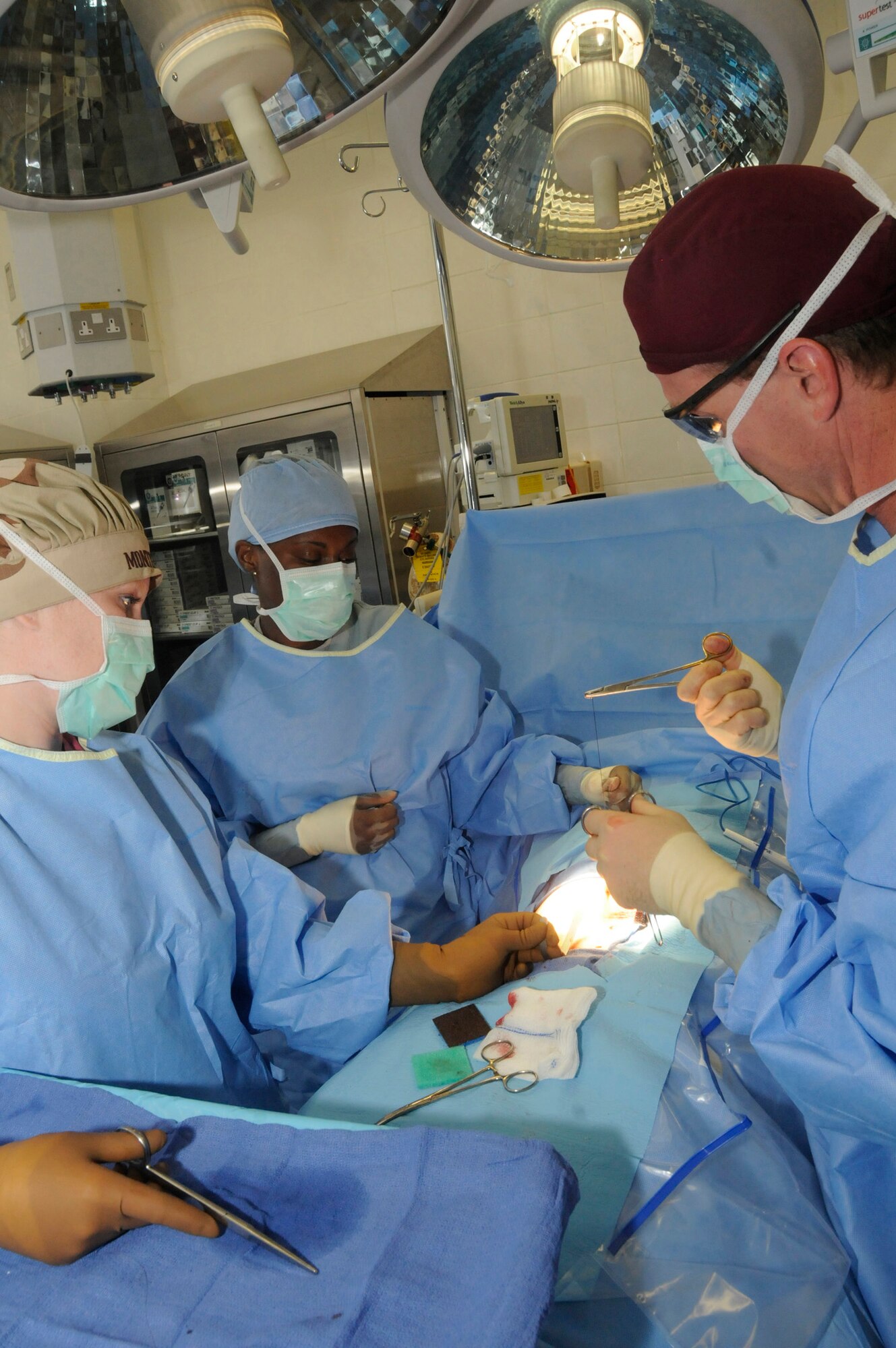 Senior Airman Cara Montgomery, surgical technician, and Senior Airman Brittney Hardrick, cardio pulmonary technician, assist Maj. Craig Kolasch, general surgeon, during the stitching of incisions after completing a laparoscopic hernia repair Dec. 23, 2008, at an undisclosed base in Southwest Asia. All Airmen are assigned to the 379th Expeditionary Medical Group. Airman Montgomery is a native of Boise, Idaho, Airman Hardrick is a native of Dayton, Ohio, and Major Kolasch is a native of Great Falls, Va. All are deployed from Keesler Air Force Base, Miss., in support of Operations Iraqi and Enduring Freedoms and Joint Task Force-Horn of Africa. (U.S. Air Force photo by Staff Sgt. Darnell T. Cannady/released)