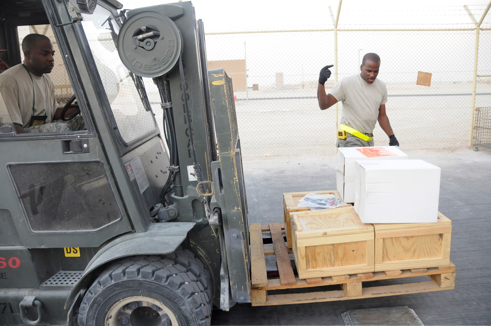 Staff Sgt. Leviticus Robinson, 379th Expeditionary Logistics Readiness Squadron Distribution Flight non-commissioned officer in charge, uses a forklift to load the priority cargo onto a scale while Senior Airman Michael Vanlear, of the distribution flight, guides him Dec. 26, 2008, at an undisclosed air base in Southwest Asia. These ELRS members are responsible for forwarding cargo received here to the area of responsibility in support of the Global War on Terrorism. Sergeant Robinson, a native of Mobile, Ala., is deployed from Keesler Air Force Base, Miss., and Airman Vanlear, a native of Oklahoma City, Okla., is deployed from Charleston AFB, S.C. Both are deployed in support of Operations Iraqi and Enduring Freedom and Joint Task Force-Horn of Africa. (U.S. Air Force photo by Staff Sgt. Darnell T. Cannady/Released)