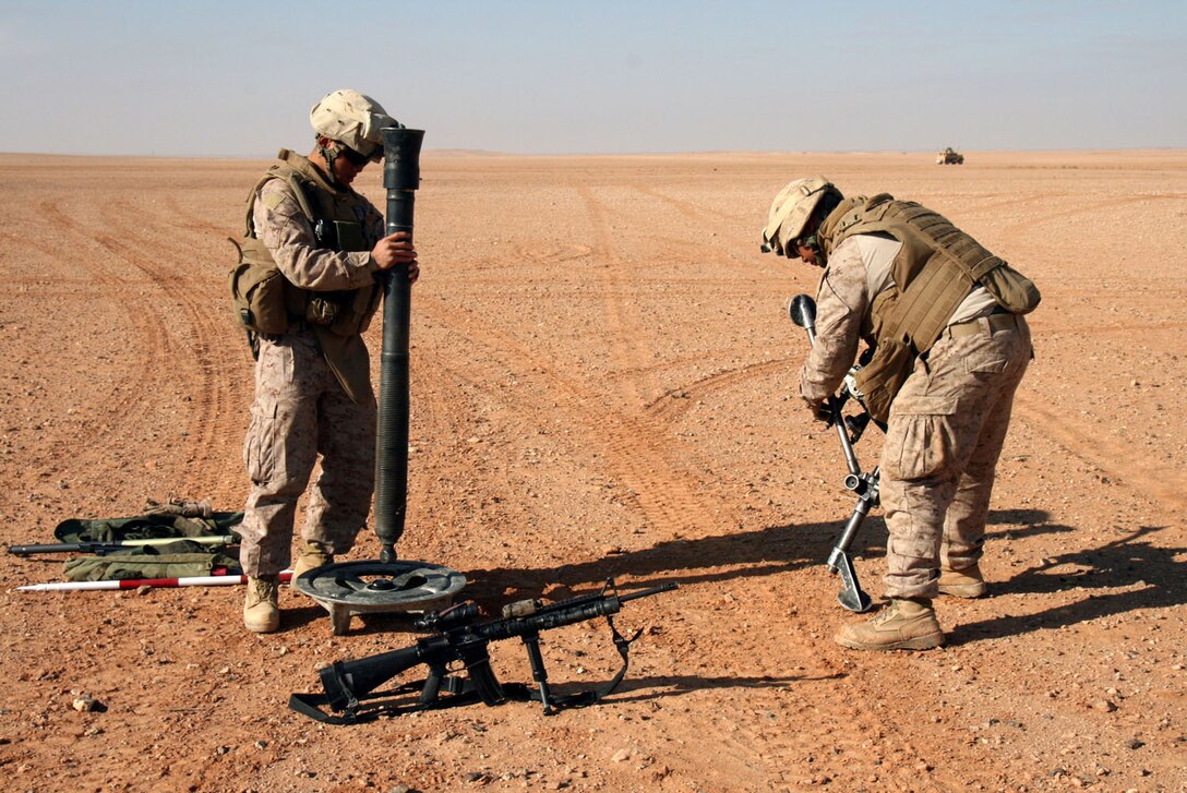 Lance Cpl. Youngjun Choi (left) and Lance Cpl. Rafael Diaz, mortarmen with Weapons Company, 2nd Battalion, 25th Marine Regiment, Regimental Combat Team 5, set up an 81mm mortar gun prior to a live-fire exercise designed to keep skills sharp in their military occupational specialty.  The range was set up in a barren stretch of desert in Iraq's western al-Anbar province.::r::::n::