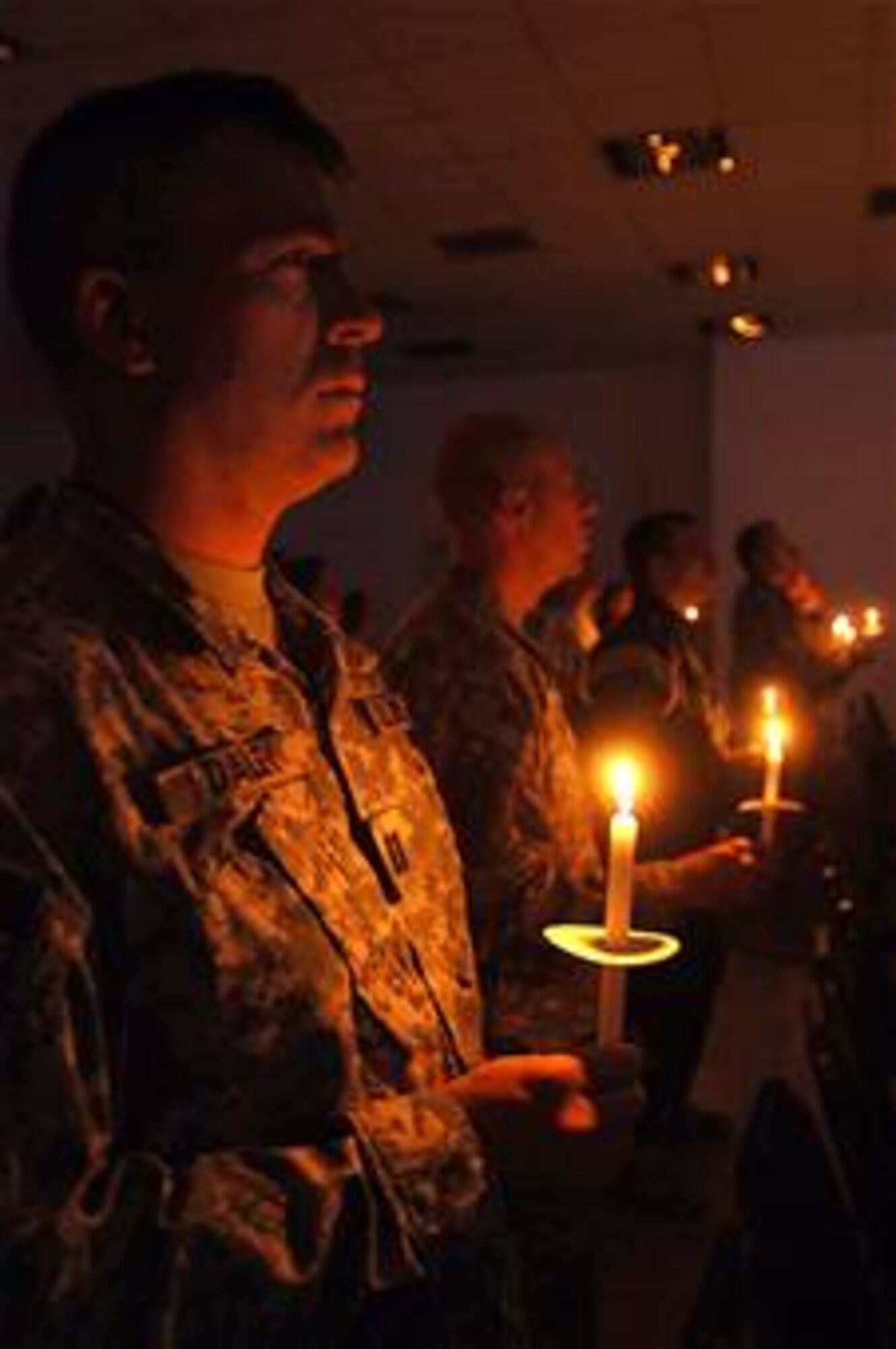 Army Capt. Jeffrey Daley and other servicemembers celebrate Christmas Eve during a candlelight service in Gilbert Memorial Chapel at Joint Base Balad, Iraq. Captain Daley is the officer in charge of administrative support for the 51st Expeditionary Signal Battalion, which is deployed from Fort Lewis, Wash. (U.S. Air Force photo/Tech. Sgt. Erik Gudmundson)