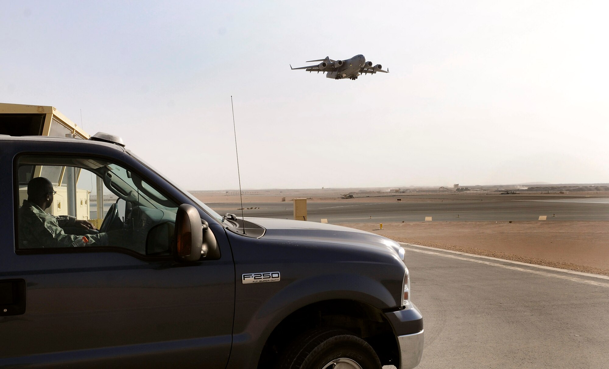Tech. Sgt. Antonio Cooper, deputy airfield manager assigned to the 379th Expeditionary Operations Support Squadron at an air base in Southwest Asia, observes a C-17 Globemaster III coming in for a landing Dec. 15.  After the aircraft has landed, Sergeant Cooper inspects the runway for debris.  The runway is checked at least once every two hours and more often when needed.  Sergeant Cooper is a native of Stapleton, Ga., and is deployed from Patrick Air Force Base, Fla. (U.S. Air Force photo/Tech. Sgt. Michael Boquette)