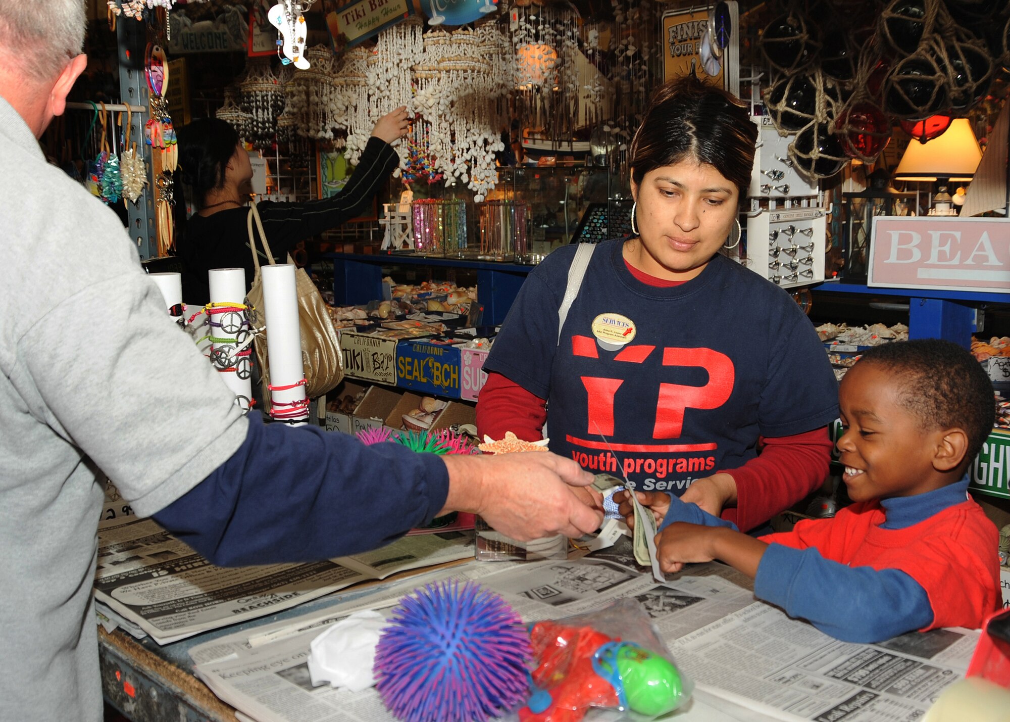 Alma Lopez (center) assists Khalid Arnold at the counter as he buys gifts at the shell shop in Seal Beach, Calif., Dec. 23. The group from Los Angeles Air Force Base Youth Services went on a holiday shopping field trip to buy gifts for friends and family, where they encountered a surfing Santa, shopped at the local shell store, and enjoyed some ice cream. (Photo by Joe Juarez)