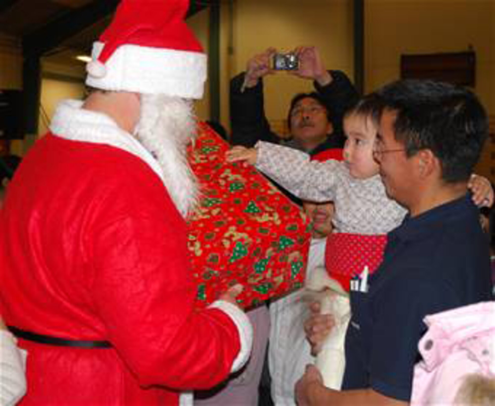 Julemand, or "Santa Claus" in Danish, hands a present to a girl during Qaanaaq, Greenland's, Julemand celebration in Qaanaaq Dec. 20. A year of fundraising at Thule, called Operation Julemand, culminates in this event where nearly 300 gifts are given out and thousands of dollars donated to local communities. Started in 1959, Operation Julemand is a humanitarian program organized and supported by all members of Team Thule – American, Danish, Greenlandic and Canadian - to give back to the local Greenlandic community. Members of Team Thule flew to Qaanaaq to participate in the celebration which included a visit from Santa, singing and gift exchange. Three other Inuit villages also receive money from Operation Julemand donations (Photos by 1st Lt. Lisa Meiman).