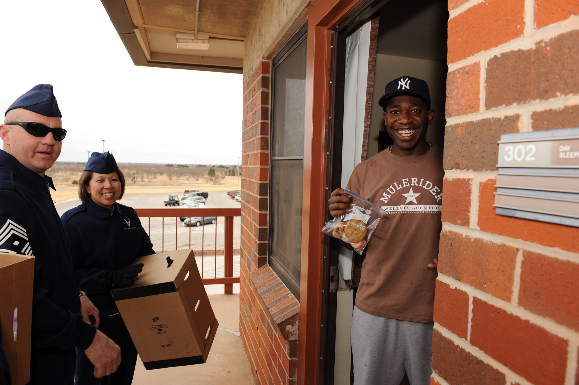 DYESS AIR FORCE BASE, Texas -- Chief Master Sgt. Kenneth Simonton, 7th Aircraft Maintenance Squadron first sergeant, and Master Sgt. Josephine Krieger, 7th Civil Engineer Squadron first sergeant, deliver cookies to dormitory resident Airman 1st Class Mike Maddison, 7th AMXS, Dec. 20. The first shirts collect cookies every December to "drop" to Airmen who may be away from home during the holidays. (U.S. Air Force photo/Staff Sgt. Connor Estes)