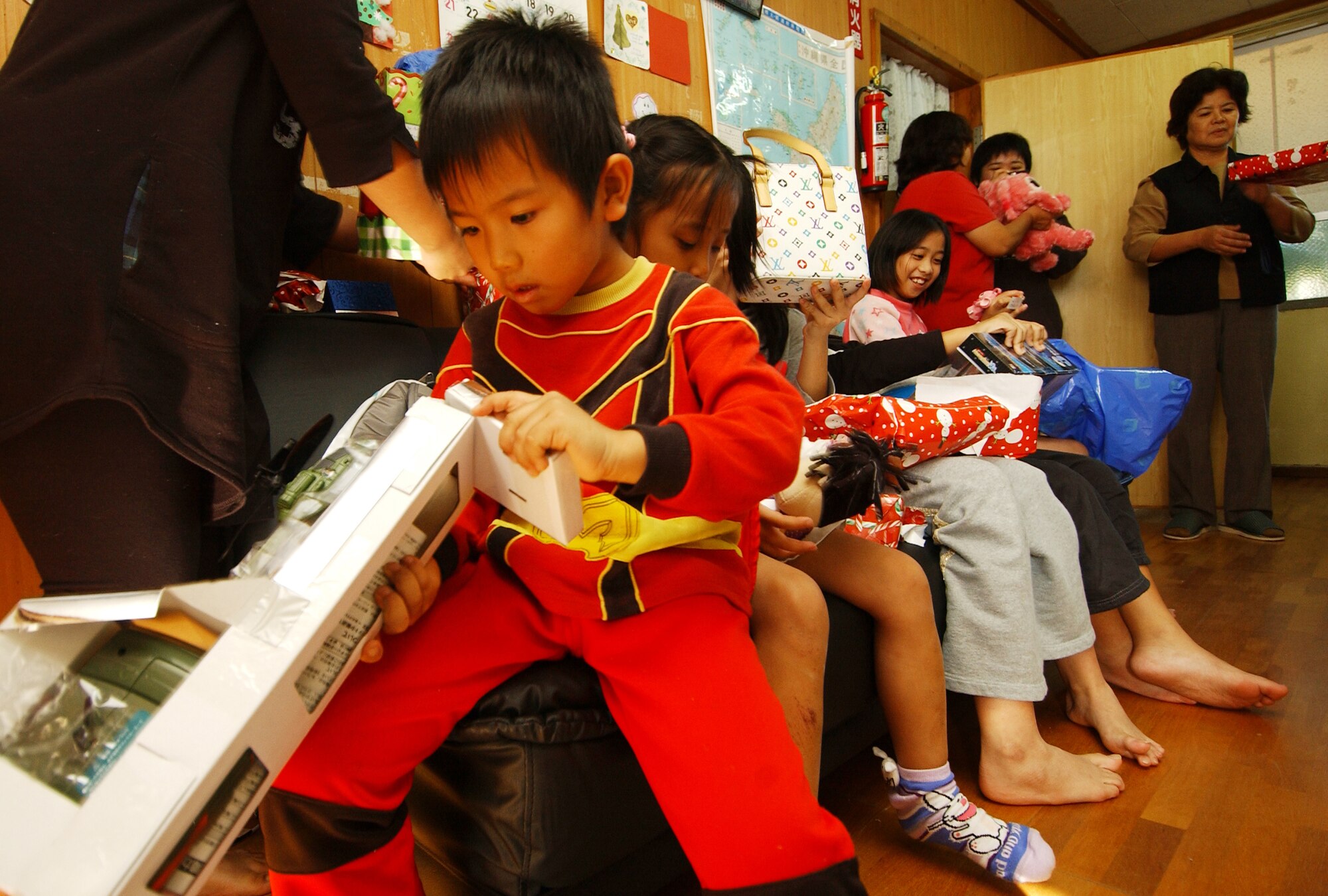 KADENA AIR BASE, Japan ? Children from Rainbow Heights open gifts donated by members from the 353rd Maintenance Squadron during a holiday visit to the facility Dec. 20. Members from the squadron donated toys for children, sports balls, and some essential items that were requested like cleaning supplies, socks, school supplies and blankets during the visit. Rainbow Heights is part of the Okinawa Single Mothers Program, a government program designed to provide temporary assistance to low-income single mothers and their children who are victims of circumstances including domestic abuse and abandonment. (U.S. Air Force photo by Tech. Sgt. Rey Ramon)                               