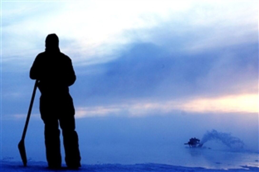 U.S. Air Force Airman 1st Class Alexandre Leseur waits while the water pumps flood a small section of the ice bridge and it starts to freeze. He will then move the water pumps to the next designated area, Fairbanks, Alaska, Dec. 23, 2008. Leseur is assigned to the 354th Civil Engineer Squadron range maintenance, Eielson Air Force Base, Alaska.