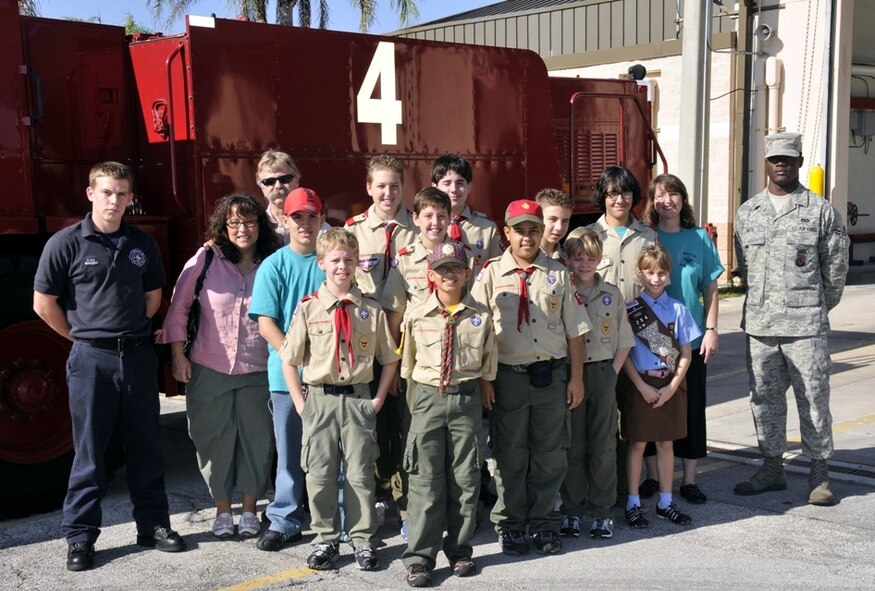 Homestead ARB fighter fighters, Mr. Jeffery Curl, far left, and Airman 1st Class Travis Smith, far right, 482nd Civil Engineering Squadron, pose for a group picture with kids and chaperones from Boy and Girl Scout Troop 599 on Dec. 30.  The Miami Scouts were treated to a tour of the base fire department and air traffic control tower; watched four F-16 fighter jets take-off; and then ate lunch at the Falcons Nest Club.  Homestead ARB offers two tours a month. Groups interested in touring the base should contact the 482nd Fighter Wing Public Affairs Office at least 60 days in advance. The PA office can be reached at (305) 224-7330. (U.S. Air Force photo/Tim Norton)