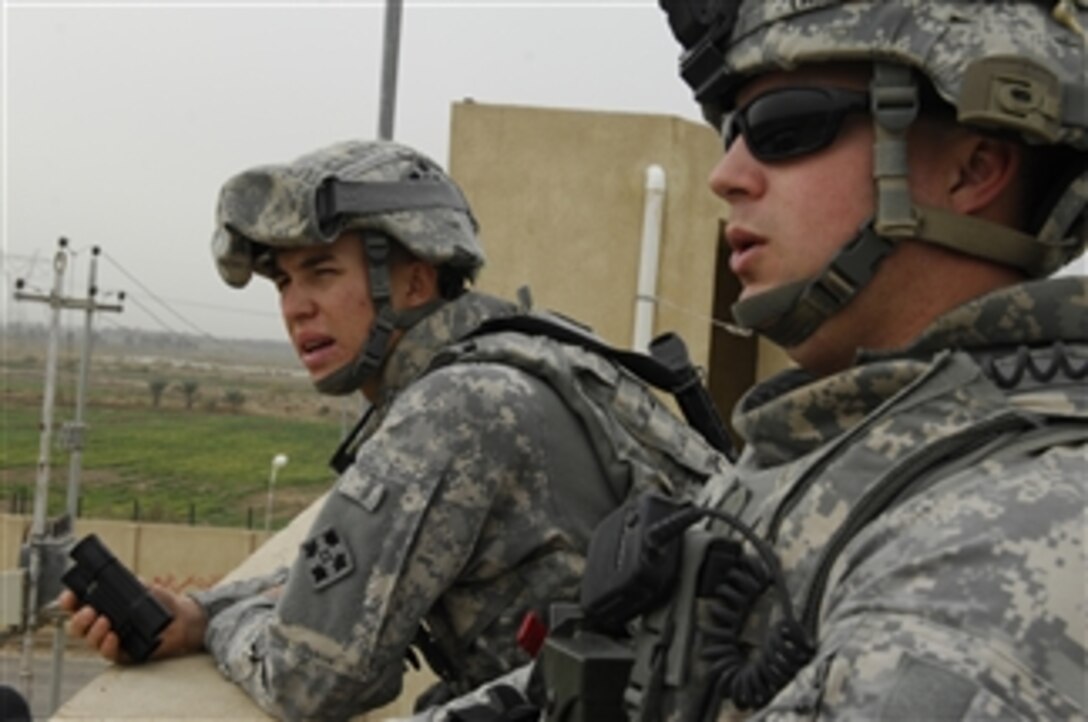 U.S. Army Sgt. Robert Taylor and Spc. Bartholomew Sherwood of 16th Field Artillery Regiment, 4th Infantry Division, watch for unusual activity from atop the Iraqi Highway Police station in the city of Albo Abdullah in Babel Province, Iraq, on Dec. 23, 2008.  