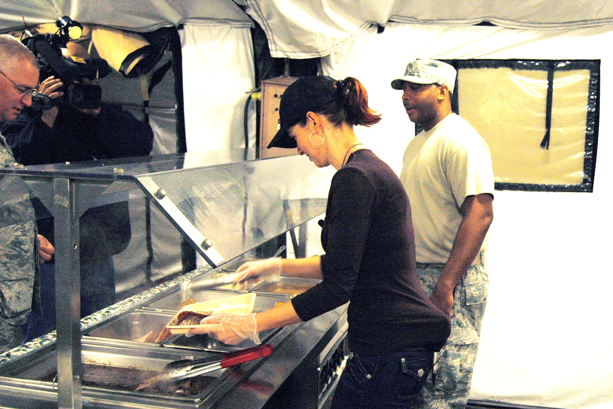 Ms. Dagmar Midcap, CBS46 reporter and chief meteorologist, tries her hand at serving Christmas dinner at the Air Force Reserve Command's Combat Services dining facility under the watchful eye of Tech. Sgt. Don Proctor, Services Combat instructor.  Air Force Services personnel are trained at the facility in preparation for field combat duty.  (U.S. Air Force photo/Master Sgt. Stan Coleman)  
