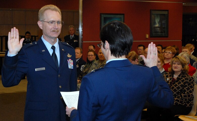 Brig. Gen. Deborah McManus, Alaska's assistant adjutant general for air, administers the military oath of office to newly promoted Brig. Gen. Charles E. "Chuck" Foster Jr. before a packed house at Kulis Air National Guard Base Dec. 18. A former rescue helicopter pilot, Foster assumed command of the 176th Wing in July. He is the unit?s 16th commanding officer and the fourth to be promoted to general officer. Alaska Air National Guard photo by 2nd Lt. John Callahan.