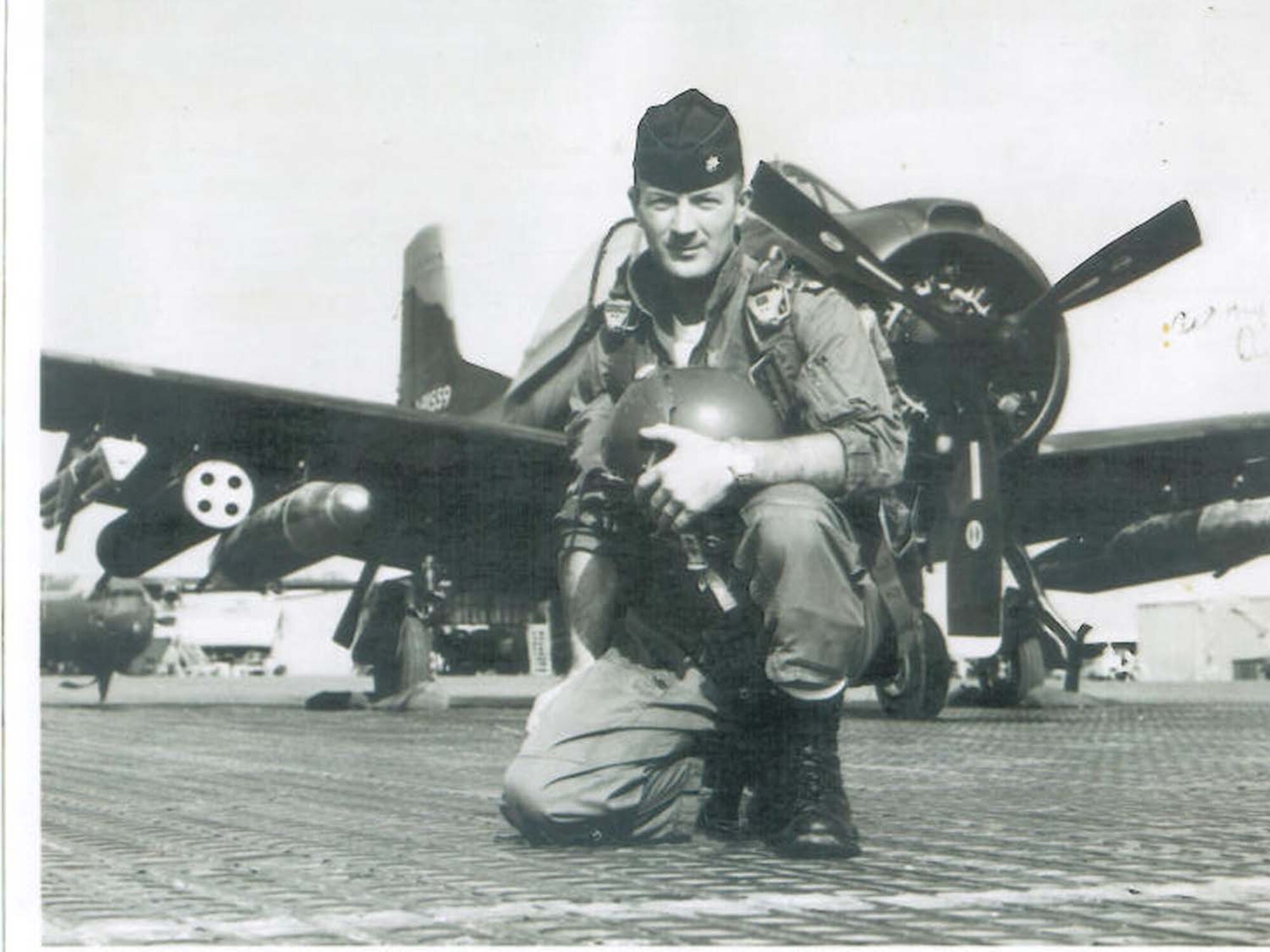 Southeast Asia-- Retired Maj. Donald Arbuckle kneels in front of a T-28D, a training aircraft which was also used for counter-insurgency missions. Arbuckle flew 162 combat missions while assigned to 606 Air Commando Squadron, the majority at night. (Courtesy photo)