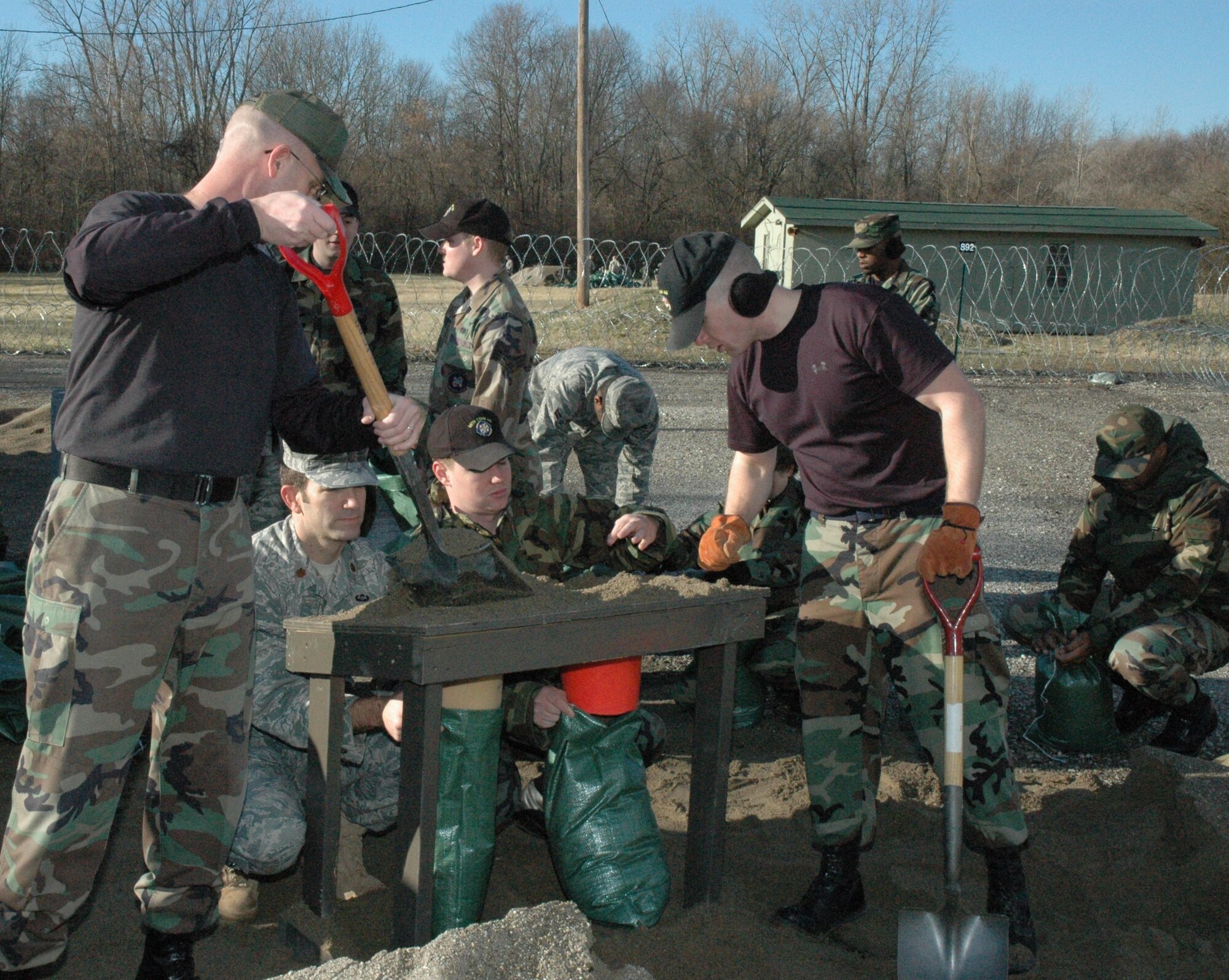 88th Air Base Wing Airmen use a wooden frame to load two sandbags at a time.  Wing members filled hundreds of sandbags to harden facilities and build defensive positions at the Warfighter Training Center on Wright-Patterson AFB, Ohio.