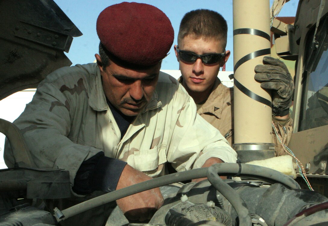 Cpl. Jaimey C. Syvruv, motor transportation mechanic, Combat Logistics Battalion 2, 1st Marine Logistics group, helps an Iraqi Soldier trouble shoot a heater problem on a High-Mobility, Multipurpose, Wheeled Vehicle during the first Iraqi partnership at the Iraq camp here, Dec. 31. ?This is the first time we worked with Iraqi Soldiers at their camp instead of our maintenance area,? said Gunnery Sgt. Duane E. Black, 38, Marceline, Mo., Motor Transportation Maintenance Platoon commander, CLB-2, 1st MLG. ?We can train more of their mechanics at the Iraqi maintenance bay because they all can?t come over to our shop.? For more than a year, Iraqi mechanics on Camp Majed aboard Al Asad have been traveling to the American side of the base for HMMWV mechanical training. No more then five Iraqi Soldiers would show up every Wednesday to learn about fixing their military vehicles. Over the last year, the Primary Iraqi Command has been focusing on Marines standing back and advising instead of fixing the vehicles for them. ?We?re here to watch over the Iraqi Soldiers and observe them work on HMMWV,? said Syvruv, 22, Blanchardville, Wis. ?We are standing back and letting them do the work so they can become more self sufficient.? With all the mechanical knowledge the Marines taught to the Iraqi Soldiers, U.S. forces will be able to leave Iraq knowing they can function as a military on their own.