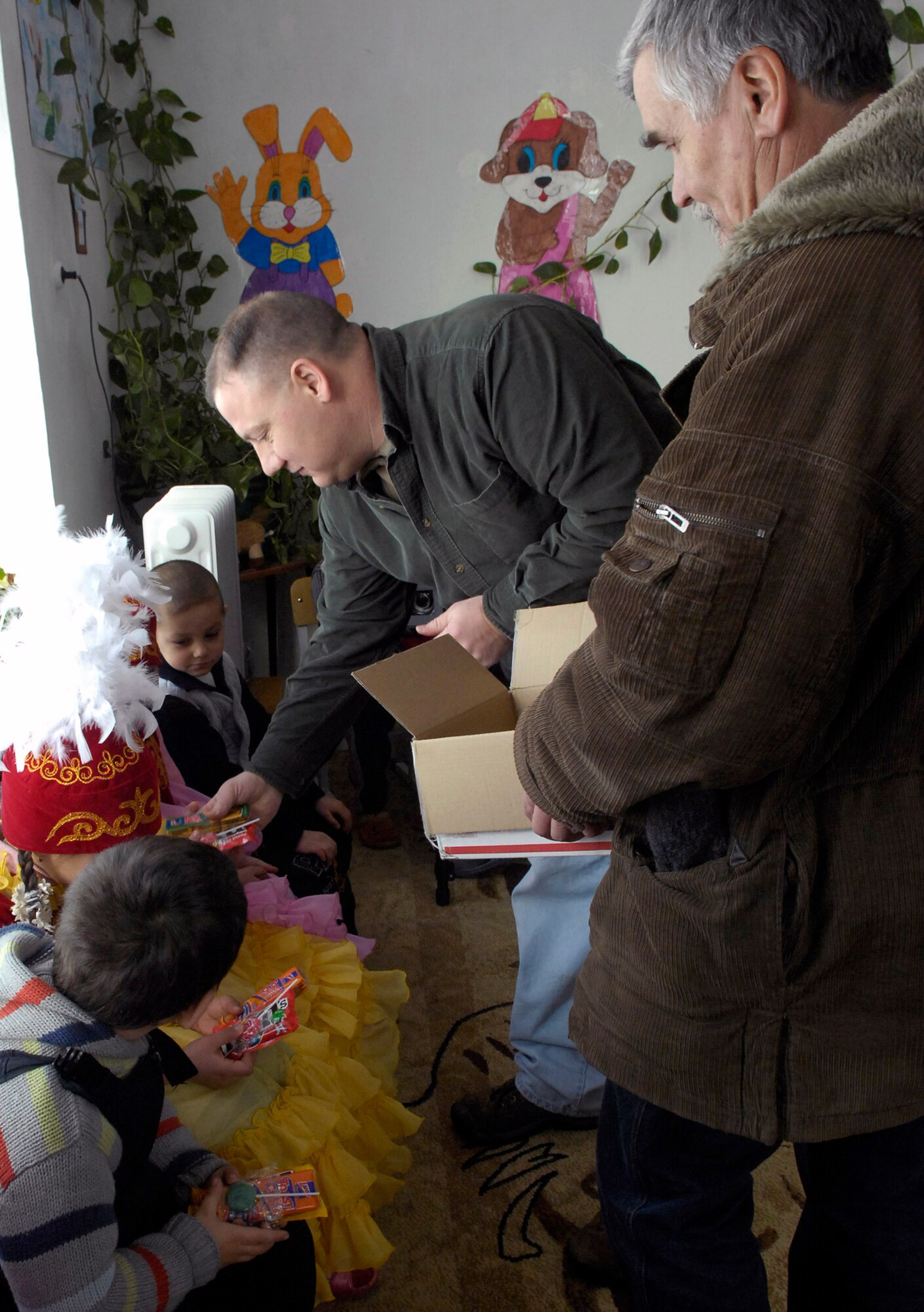 Senior Master Sgt. Reynold Albright, passes out some treats for the kids with the help of an interpreter Jan. 24 at a preschool in Vasilievka, Kyrgyzstan. Sergeant Albright is the 376th Expeditionary Operations Group superintendent and volunteers from Manas Air Base, Kyrgyzstan, installed and insulated windows in the main part of the school. Members of the 376th EOG have sponsored the nearby villages of Vinogradnoye and Vasilievka for about two years, with each air and space expeditionary force rotation spending volunteer time working for the village mayor, like making improvements at this kindergarten in Vasilievka. (U.S. Air Force photo/Senior Ariman Tabitha Kuykendall) 
