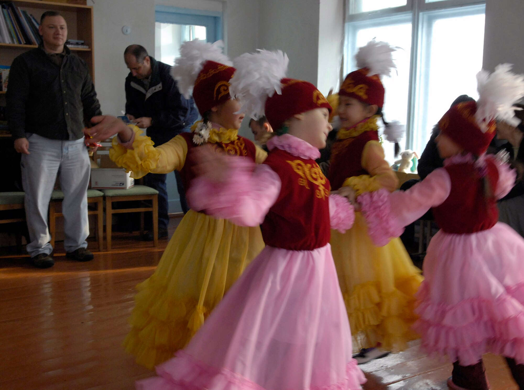 Children from the Vasilievka kindergarten class, dressed in traditional Kyrgyz garb, performed some local dances and sang songs to thank Senior Master Sgt. Reynold Albright (left) and other Airmen for their volunteer efforts at the school Jan. 24 at Vasilievka, Kyrgyzstan. Sergeant Albright is the 376th Expeditionary Operations Group superintendent and volunteers from Manas Air Base, Kyrgyzstan, fixed floors, painted and installed a hot water heater for the school. The 376th EOG also raised $2,000 for a fence to be built around a school to make a children's play area safer. (U.S. Air Force photo/Senior Ariman Tabitha Kuykendall) 
