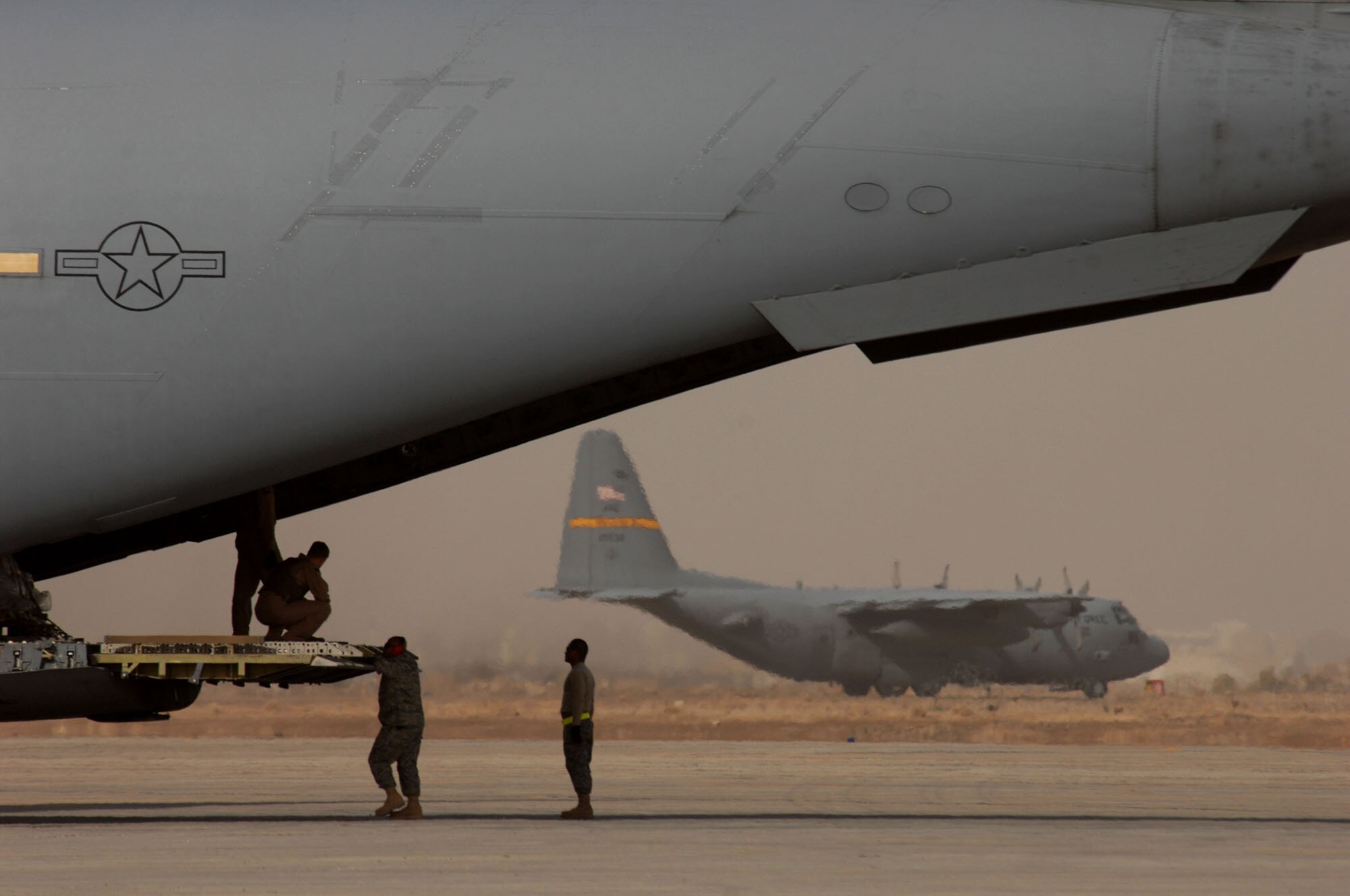 Air Force personnel wait for a pallet of equipment to load on a C-17 Globemaster III at Sather Air Base, Iraq, January 30, 2008. Sather AB is located on the west side of Baghdad International Airport and is the largest mover of passengers in Iraq, averaging 6,200 passengers weekly and the second largest mover of cargo in Iraq, averaging more than 1,700 tons weekly. (U.S. Air Force photo by Tech. Sgt. Jeffrey Allen)
