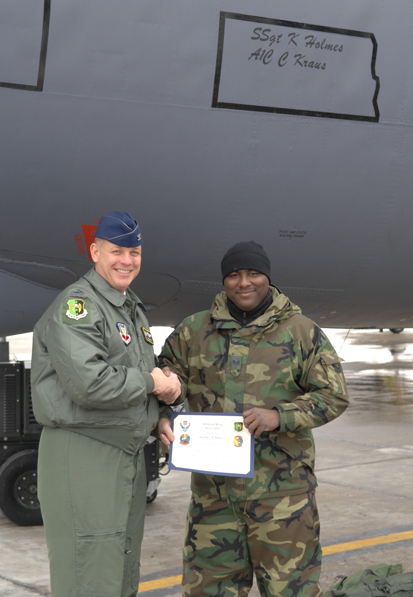 MINOT AIR FORCE BASE, N.D. -- Col. Joel Westa, 5th Bomb Wing commander, presents Staff Sgt. Kess Holmes with a certificate after Sergeant Holmes was awarded the position of dedicated crew chief to the wing flagship. (U.S. Air Force photo by Senior Airman Cassandra Jones)