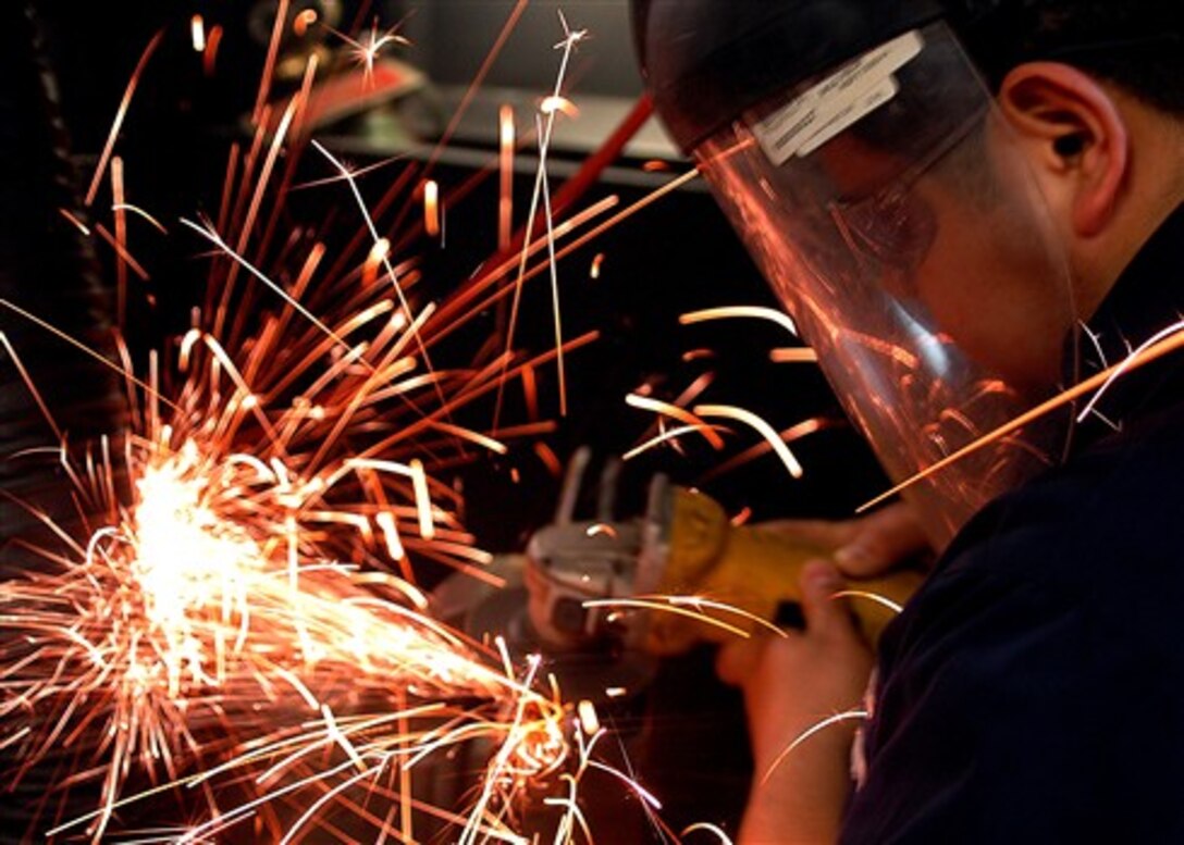 Hull Maintenance Technician Fireman Fabian Villota grinds a piece of pipe to use as a guide for mooring lines on the forecastle of the USS Theodore Roosevelt, off the coast of Virginia, Jan. 30, 2008.   