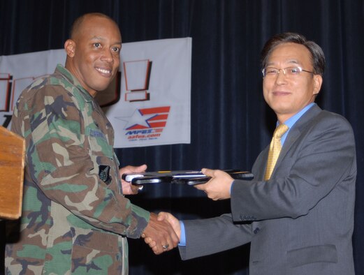KUNSAN AIR BASE, South Korea -- Col. C.Q. "Wolf" Brown, 8th Fighter Wing commander presents Mr. Jung, Soo-hyun, COO Hyundai Engineering with a plaque as a token of appreciation for Hyundai Engineering's dedication to the new theater project during the theater grand opening here Feb. 1.  The new theater has 200 more seats than the previous theater that was built in 1962.  The increase in capacity will enable the Wolf Pack to accept follow on forces more efficiently.  (U.S. Air Force photo/Staff Sgt. Darcie Ibidapo)