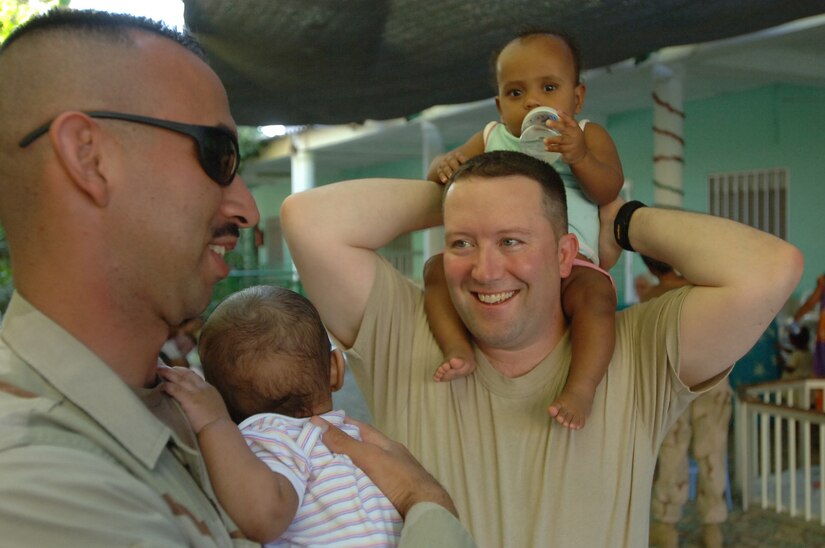DJIBOUTI – Air Force Staff Sgt. Francisco Hernandez (left) and Maj. Lanny Greenbaum enjoy playing with children at a Djibouti orphanage near Camp Lemonier, Djibouti. Greenbaum, a Plain City, Ohio, native, is the Combined Joint Task Force-Horn of Africa information management officer, and Hernandez, a Merkel, Texas, native, is the CJTF-HOA Information Management Office Data Systems noncommissioned officer in charge. Servicemembers supporting the CJTF-HOA mission donate their time three times a week to help French nuns who run the facility feed the babies at dinner time. More than 60 babies and toddlers are cared for at the facility. (U.S. Air Force photo/Staff Sgt. Jennifer Redente)